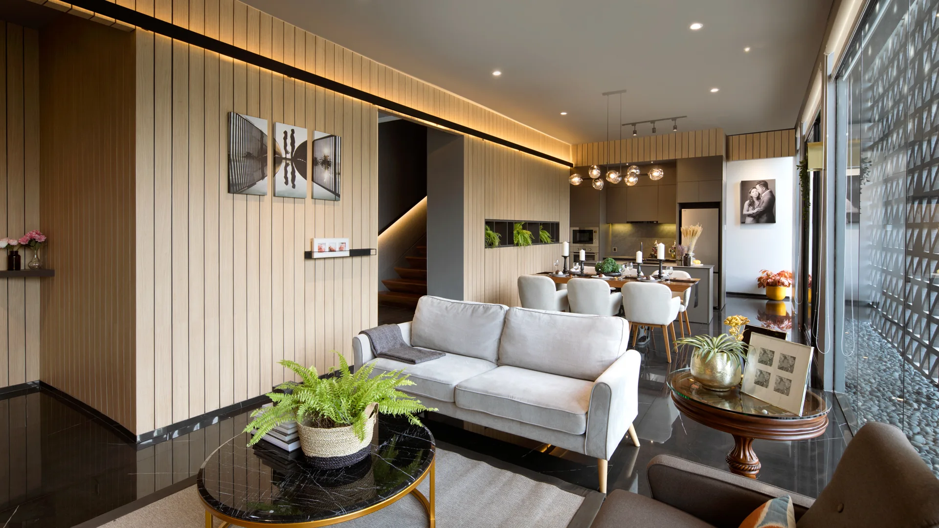 A modern open living room features light wood slat wall paneling, a gray sofa, and a black marble coffee table on a glossy dark tiled floor.