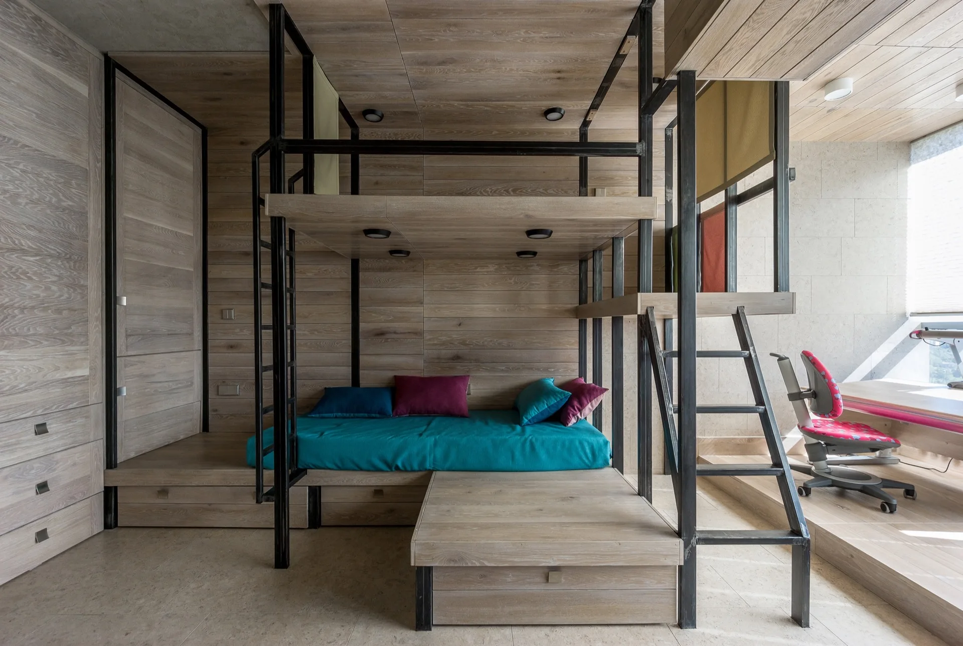A kids' bedroom features a custom wooden bunk bed structure with a dark metal frame, integrated desk area, and matching wood-paneled walls.