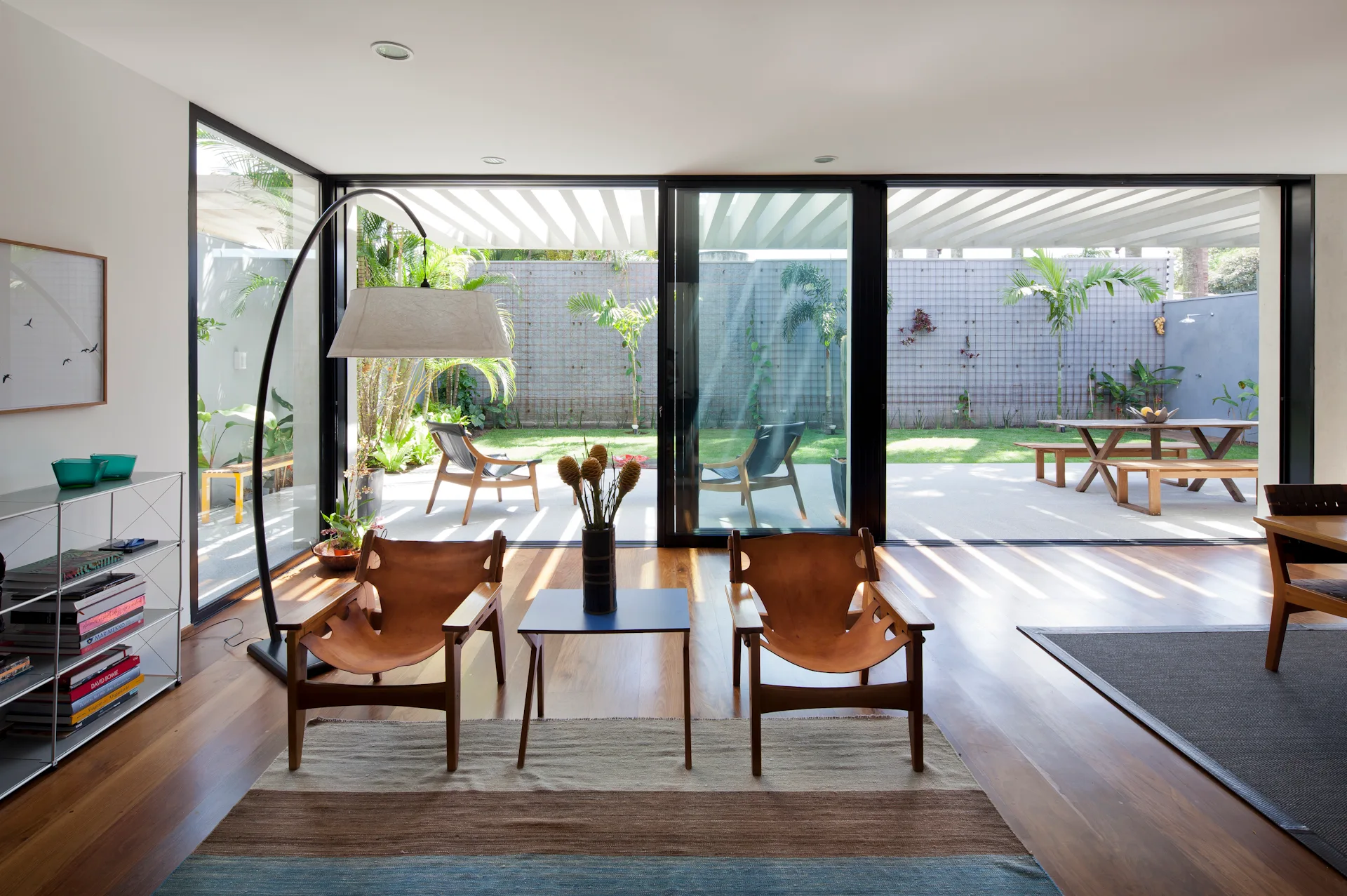 Two tan leather lounge chairs sit on a striped rug in front of large sliding glass doors opening to a backyard patio.