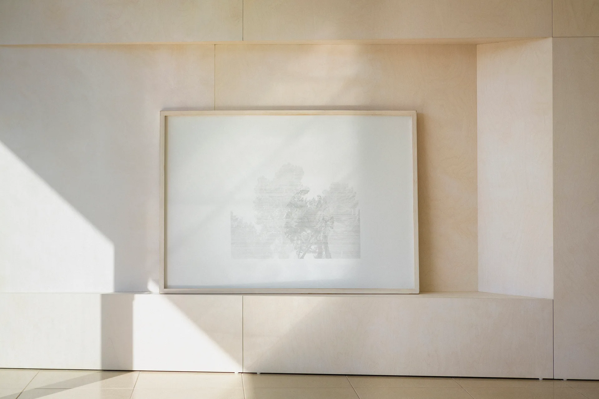 A light wood paneled wall featuring a large recessed niche with a wood-framed landscape art print leaning inside.