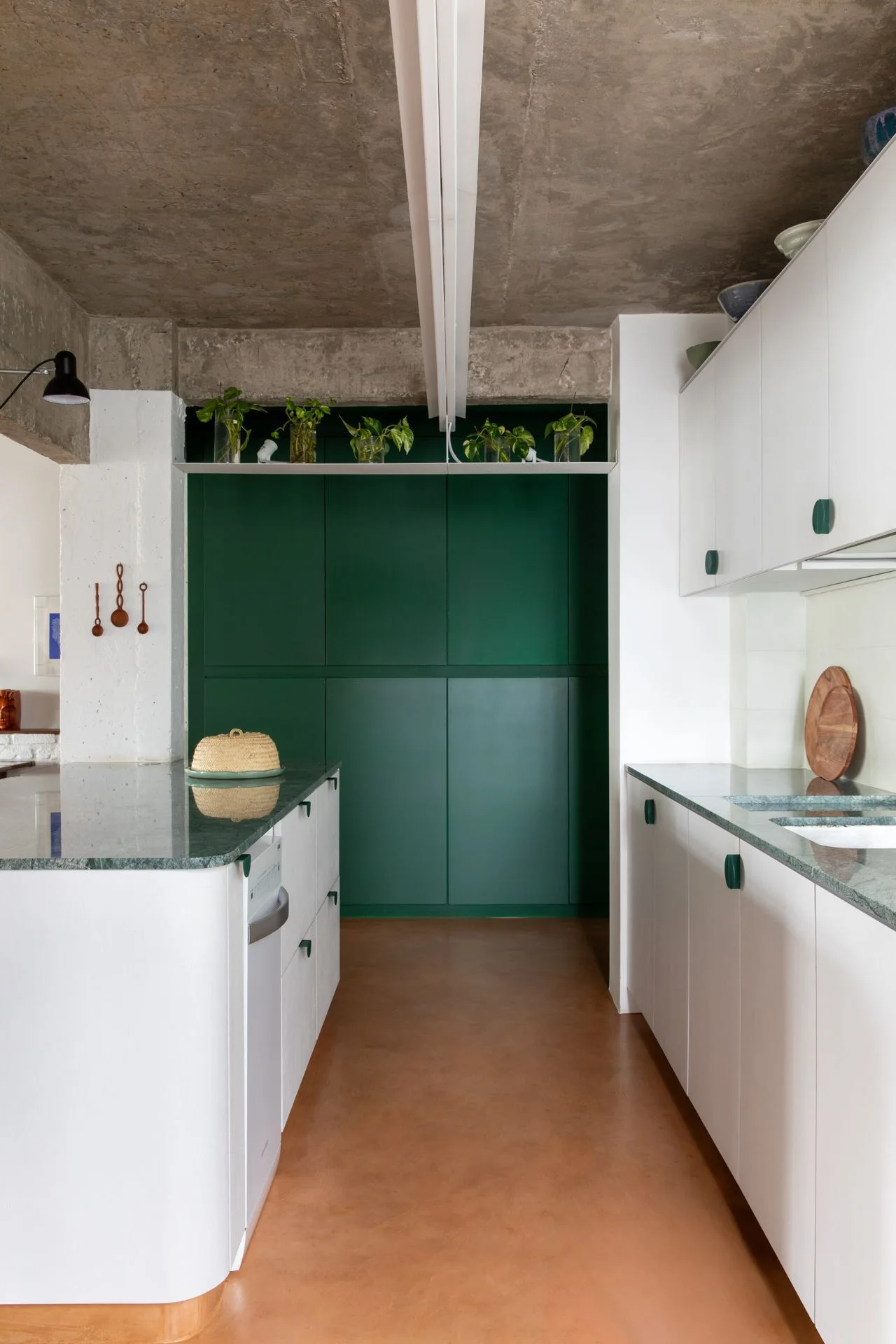 A contemporary kitchen featuring white cabinetry, green stone countertops, a curved island, and an exposed raw concrete ceiling.