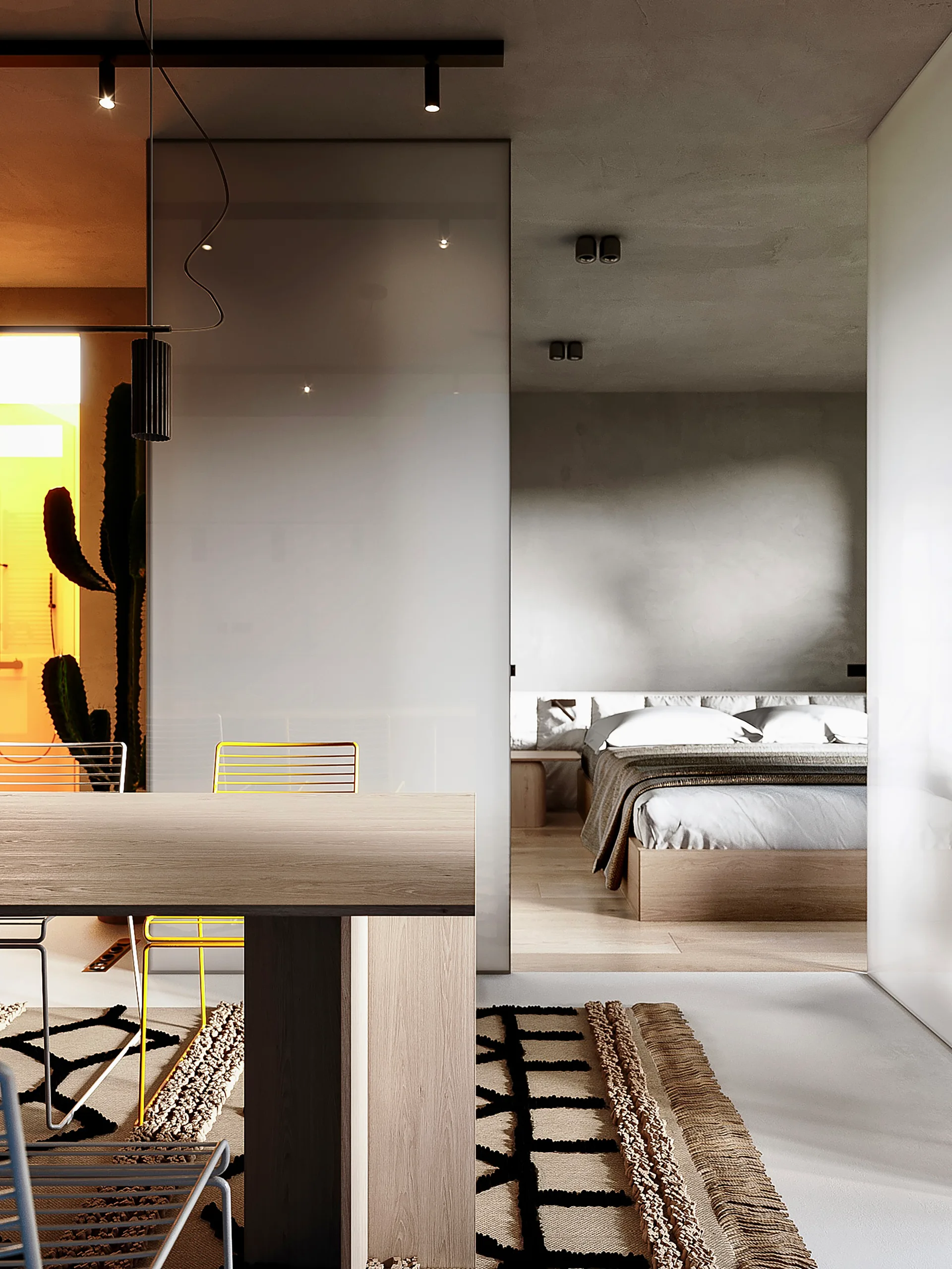 A modern bedroom with a low wooden bed is visible through a frosted glass sliding partition behind a dining table with yellow metal chairs.