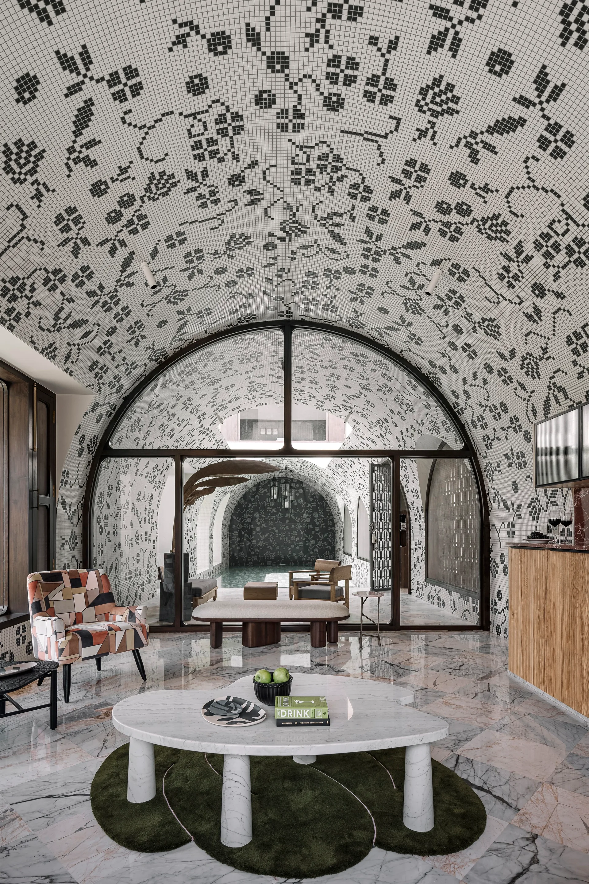 A living room features a vaulted ceiling covered in black and white mosaic tiles, a marble coffee table, and an arched glass partition.