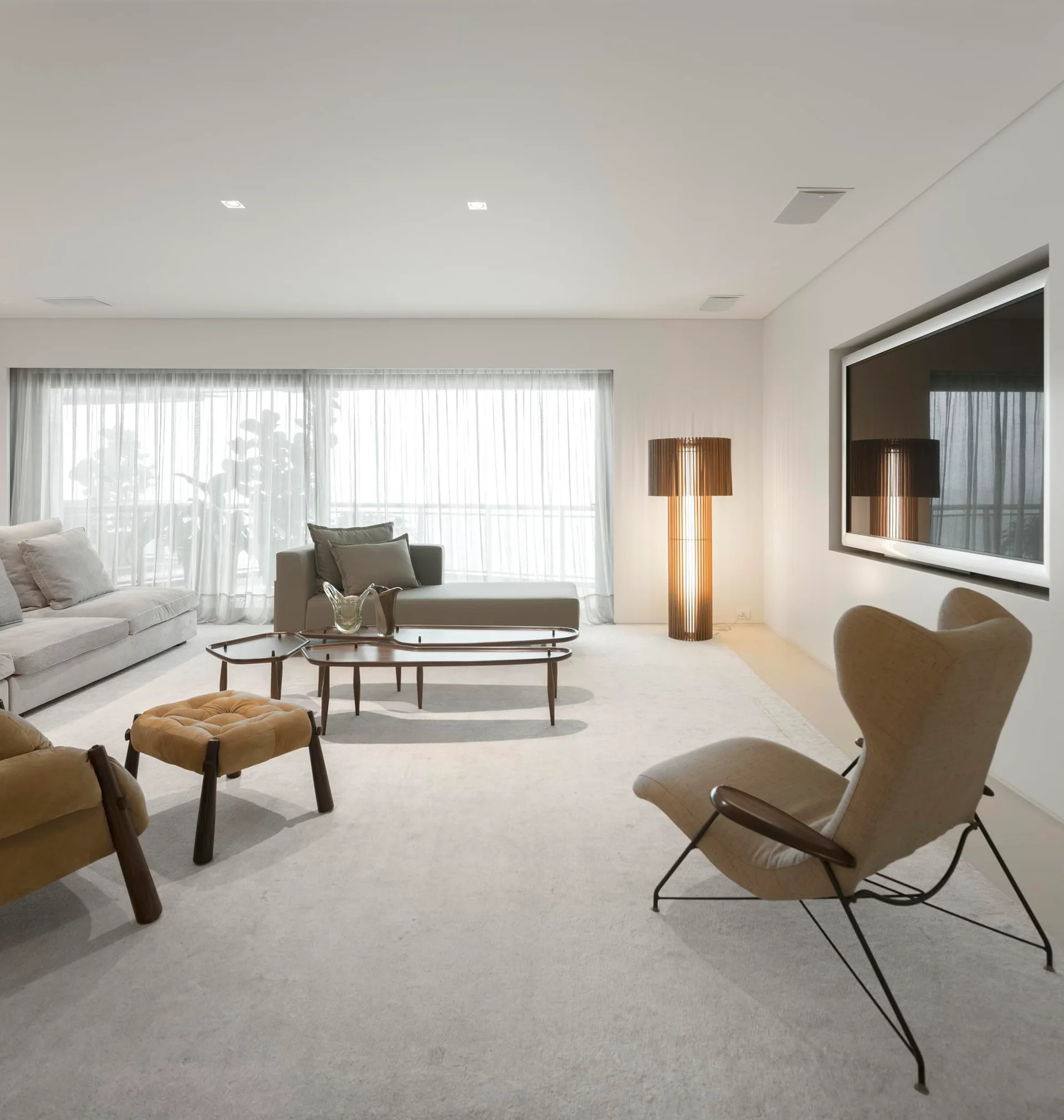 A minimalist living room with a grey sofa, mid-century modern armchairs, a wooden coffee table, and a glowing slatted floor lamp.