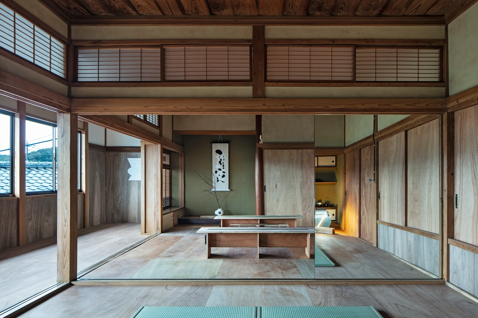 A Japanese style room features tatami mats, wooden sliding doors, a green alcove, and a large mirrored partition reflecting the wooden benches.