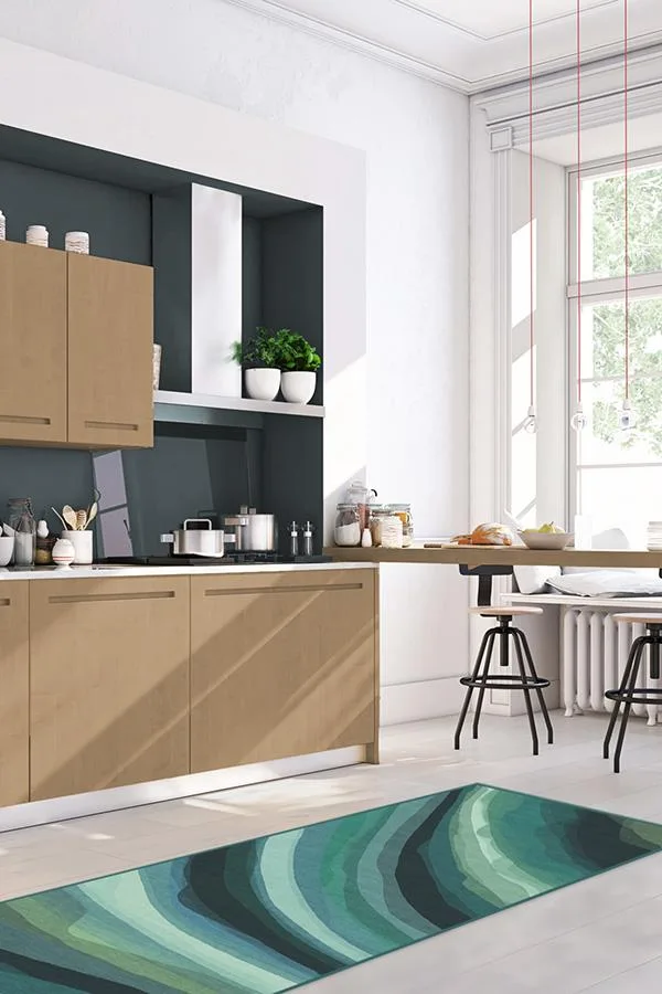 A modern kitchen with wood-toned cabinets, a dark grey recessed backsplash niche, and a patterned green wave runner rug.