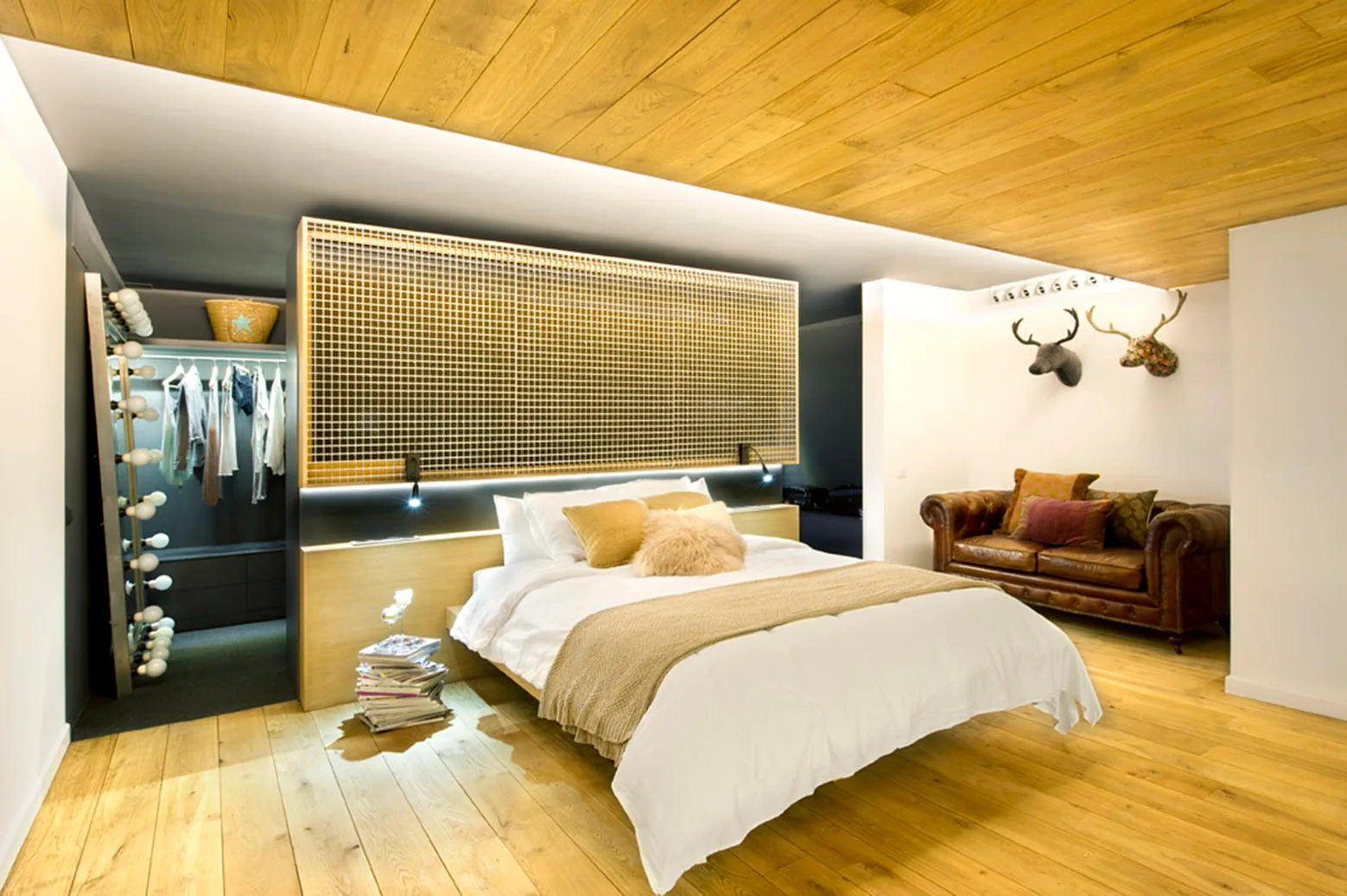 A modern bedroom featuring a wood paneled ceiling, a bed with a metal grid partition headboard, and an open walk-in closet.