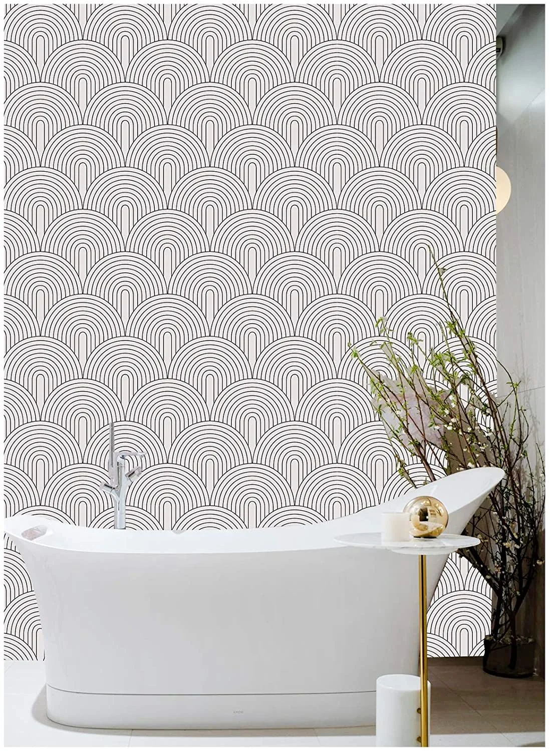 A modern white freestanding bathtub stands against a wall covered in black and white geometric arch wallpaper next to a small gold side table.