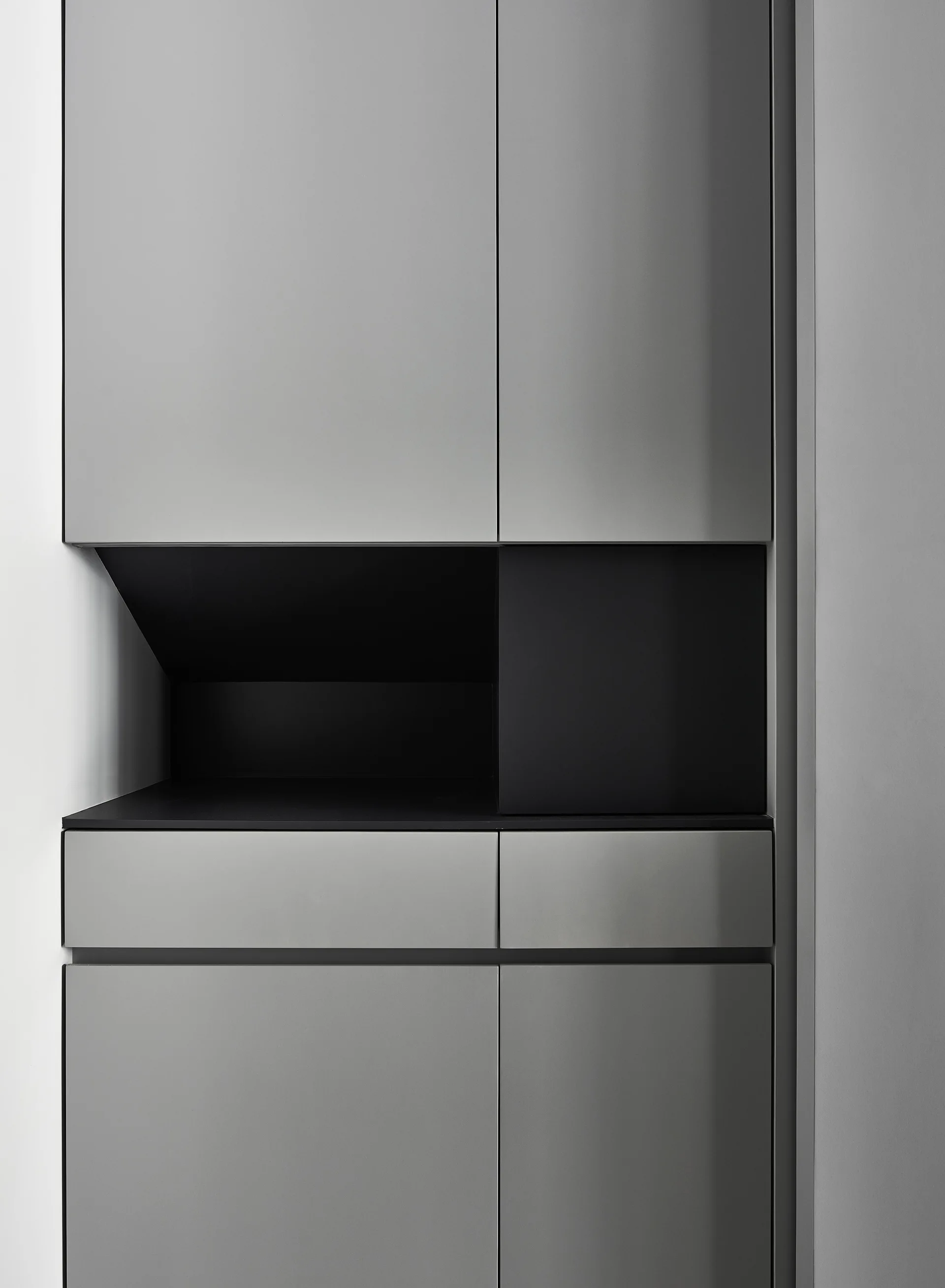 A close-up of modern matte grey kitchen cabinets featuring a recessed black horizontal shelf and flat-panel doors.