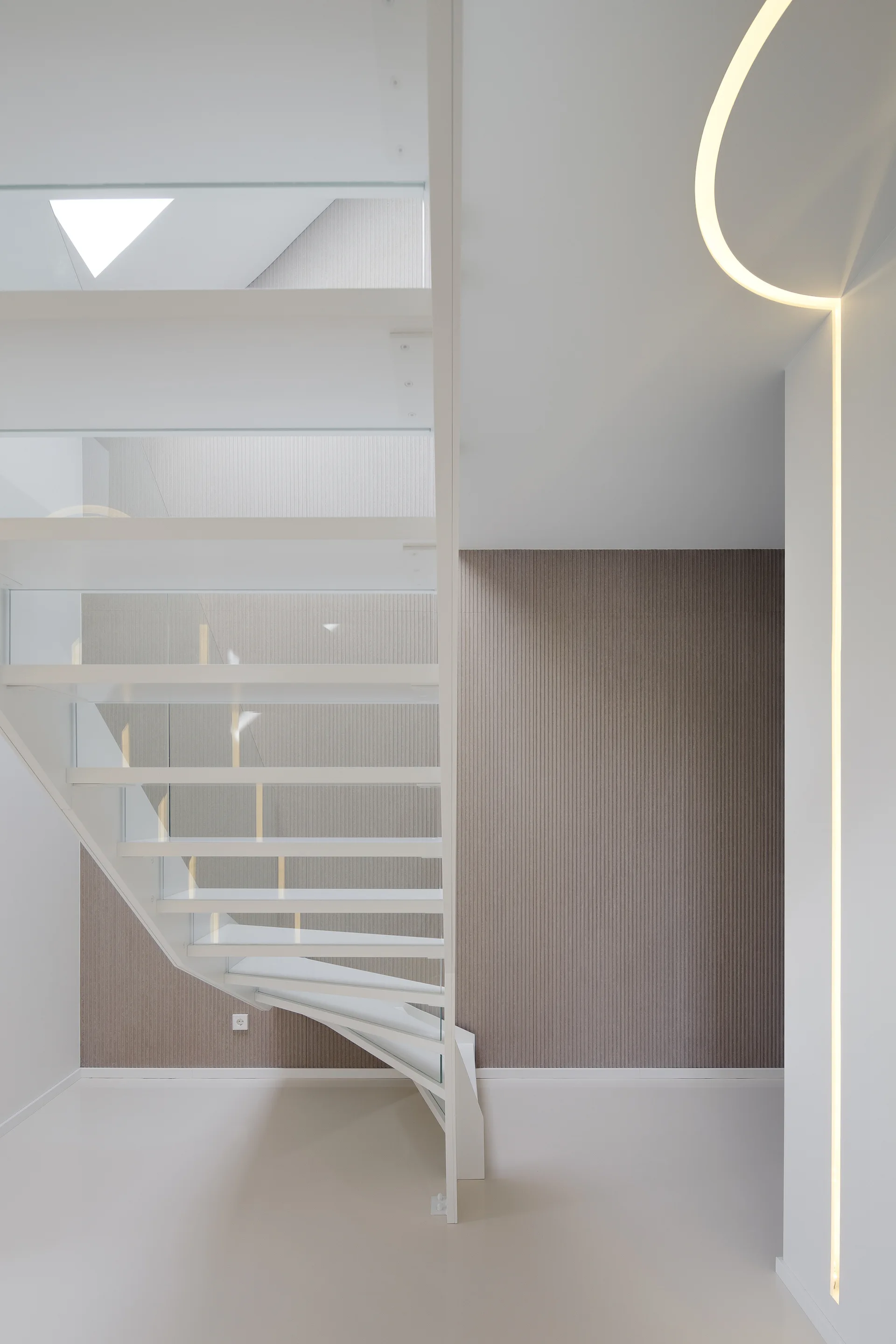 A modern white floating staircase with glass railings stands in front of a grey fluted wall panel highlighted by an integrated LED light.