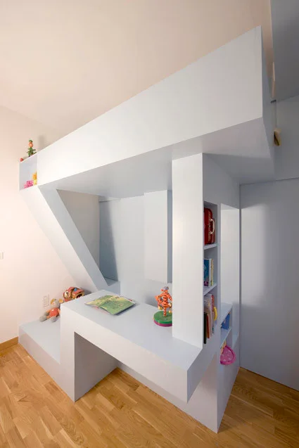 A custom light blue loft bed structure features an integrated study desk and built-in shelving over wood floors.