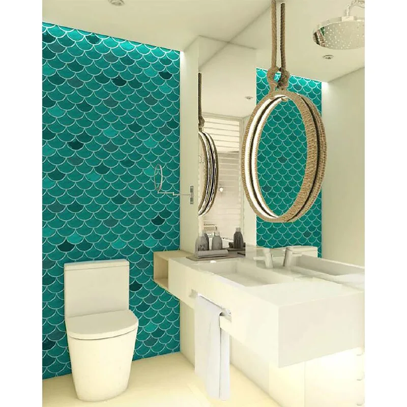 A modern bathroom features a teal fish-scale tiled wall, a white floating vanity, and a circular mirror suspended by a thick rope.