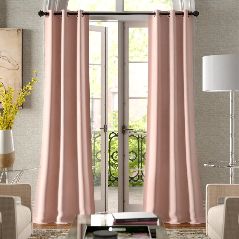 Blush pink grommet-top curtains frame a set of white French doors in a living room with textured beige wallpaper and a modern metal floor lamp.