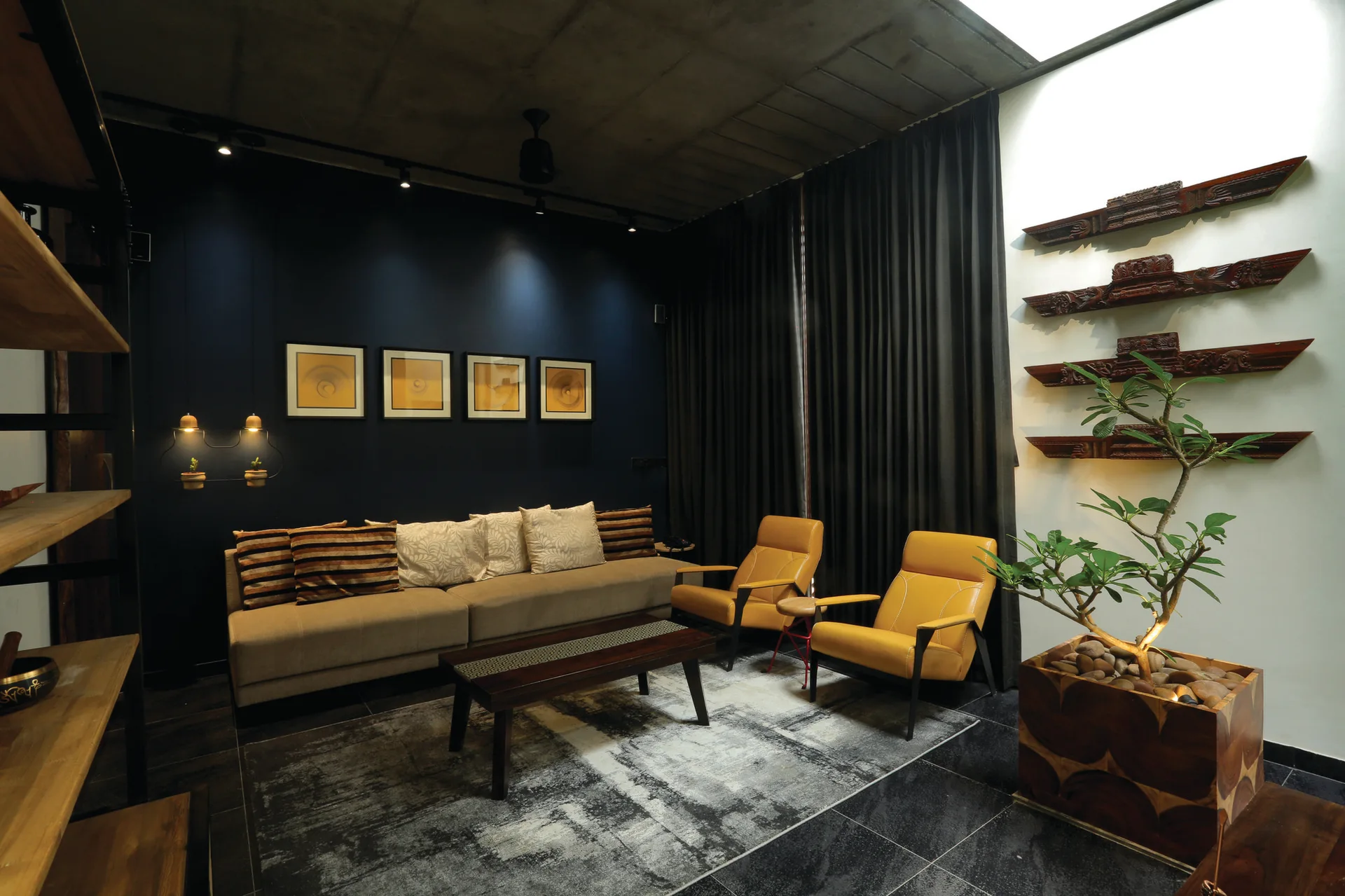 A contemporary living room featuring a beige sofa against a navy wall, two yellow armchairs, and an exposed concrete ceiling.