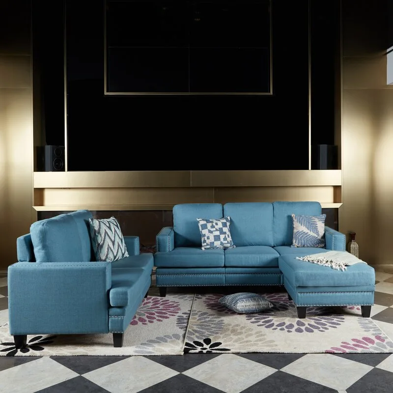 A blue upholstered sectional sofa and loveseat with nailhead trim on a floral rug over black and white checkerboard tile.