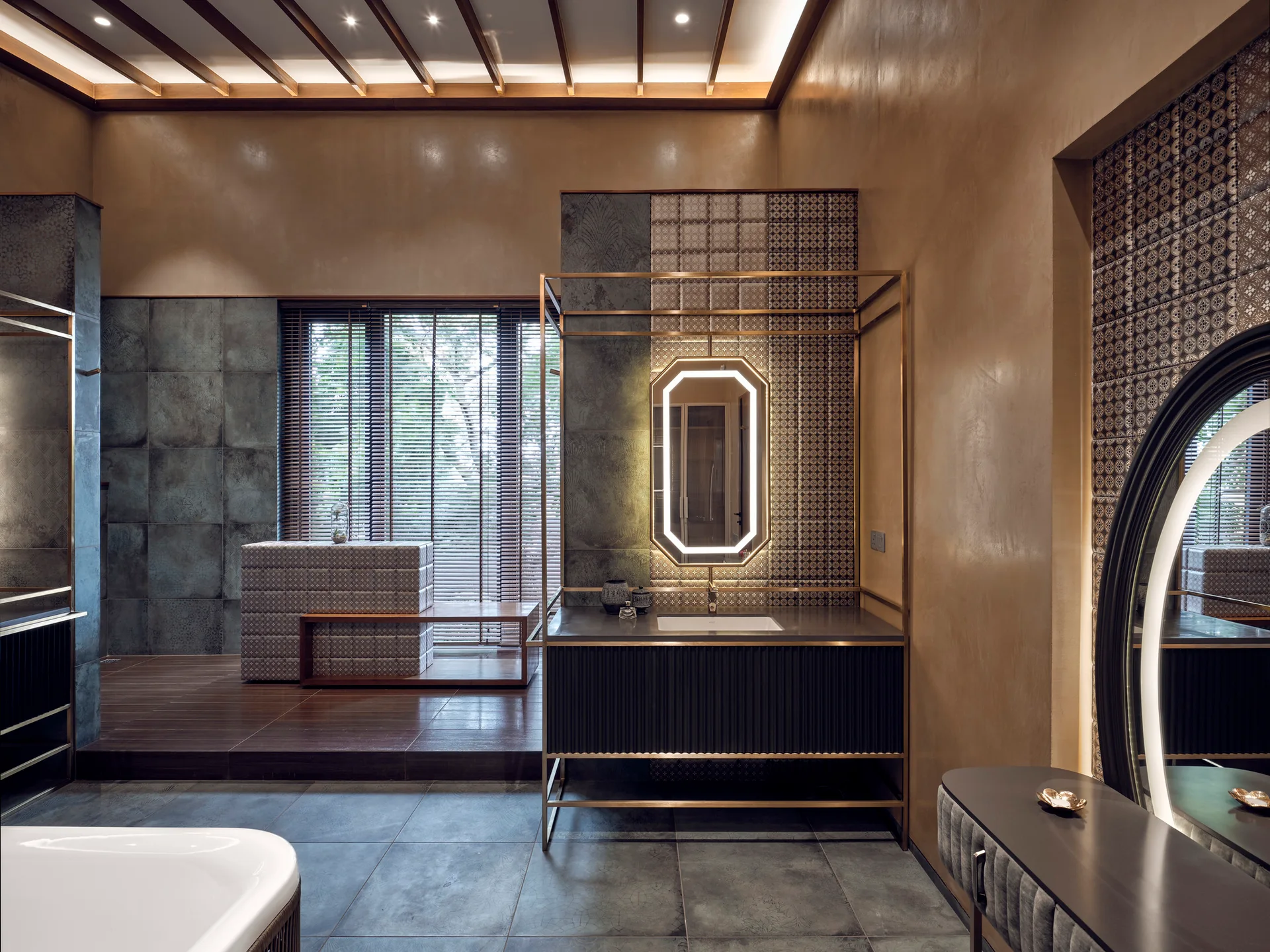 A modern bathroom vanity features a gold metal frame, an illuminated geometric mirror, patterned tile accents, and dark wood ceiling beams.