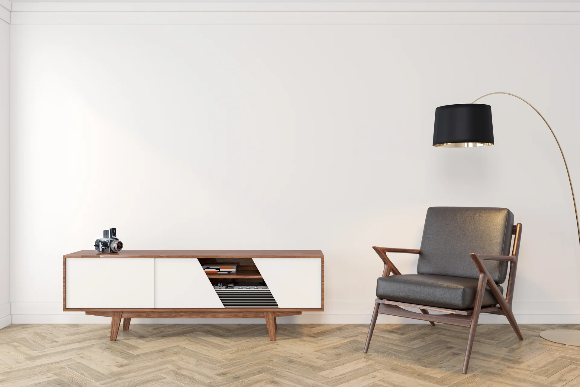 A minimalist room featuring a mid-century wooden media console, a leather armchair, and a black arc floor lamp on a herringbone wood floor.