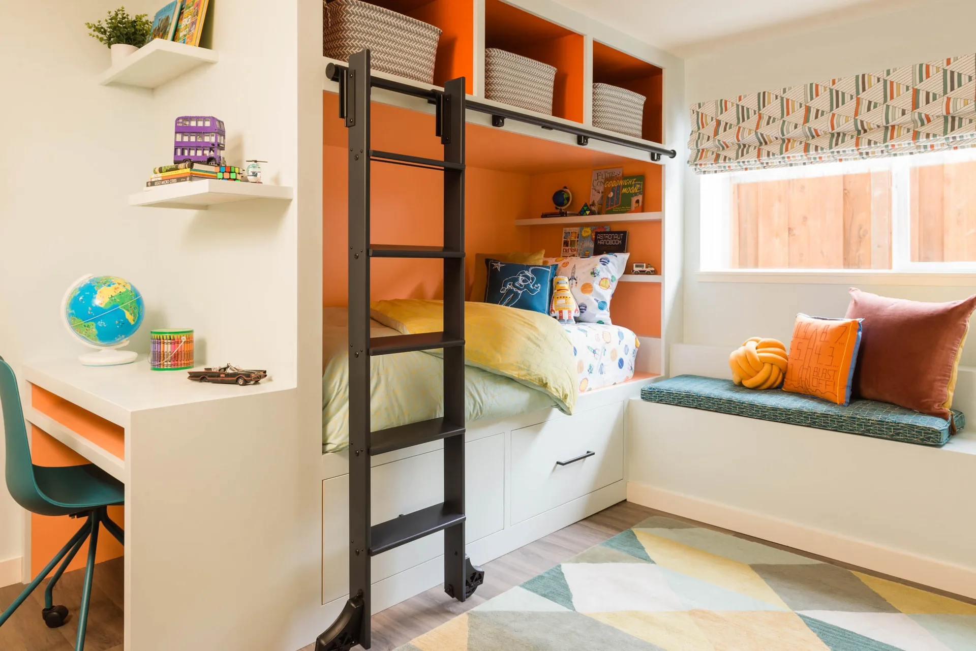 A child's bedroom features a white built-in unit containing an orange-lined bunk bed with a black sliding ladder, integrated desk, and window bench.