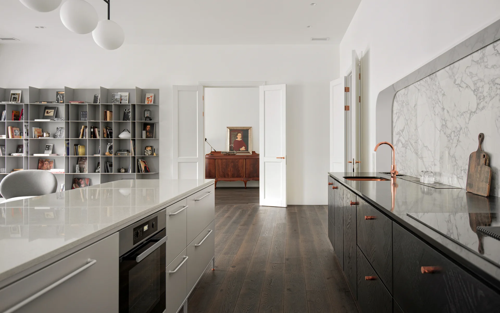 A contemporary kitchen featuring dark wood cabinetry, a light gray central island, an arched marble backsplash, and dark hardwood flooring.