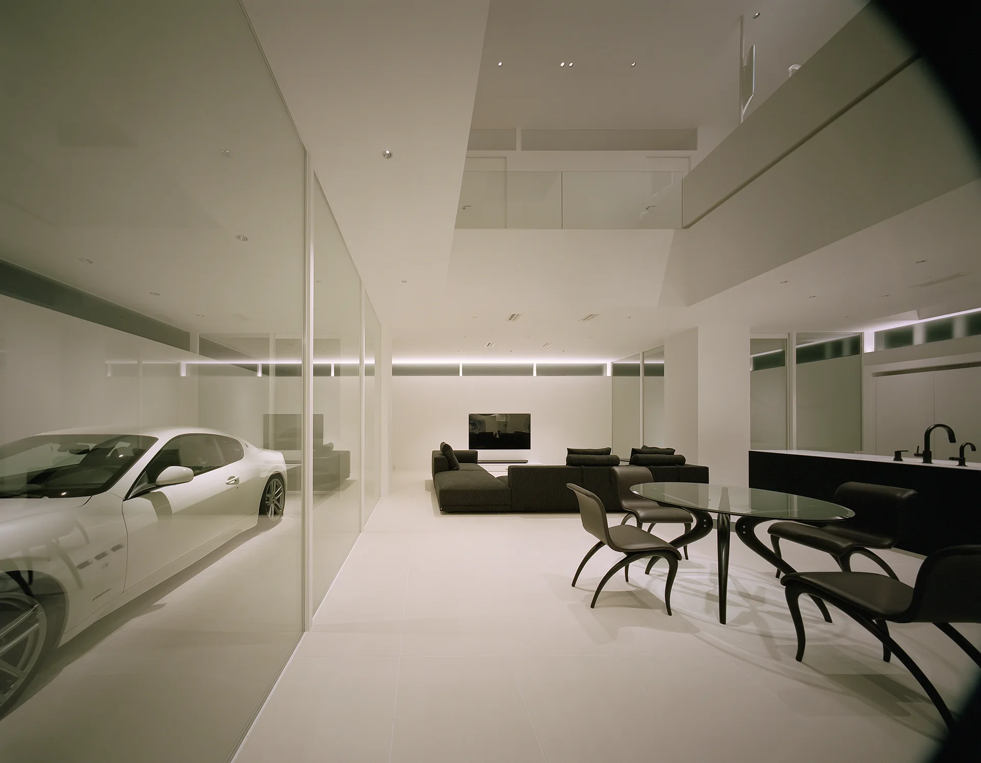A minimalist open-plan living room with a white tiled floor, dark sofa, glass dining table, and a glass-enclosed garage featuring a white car.