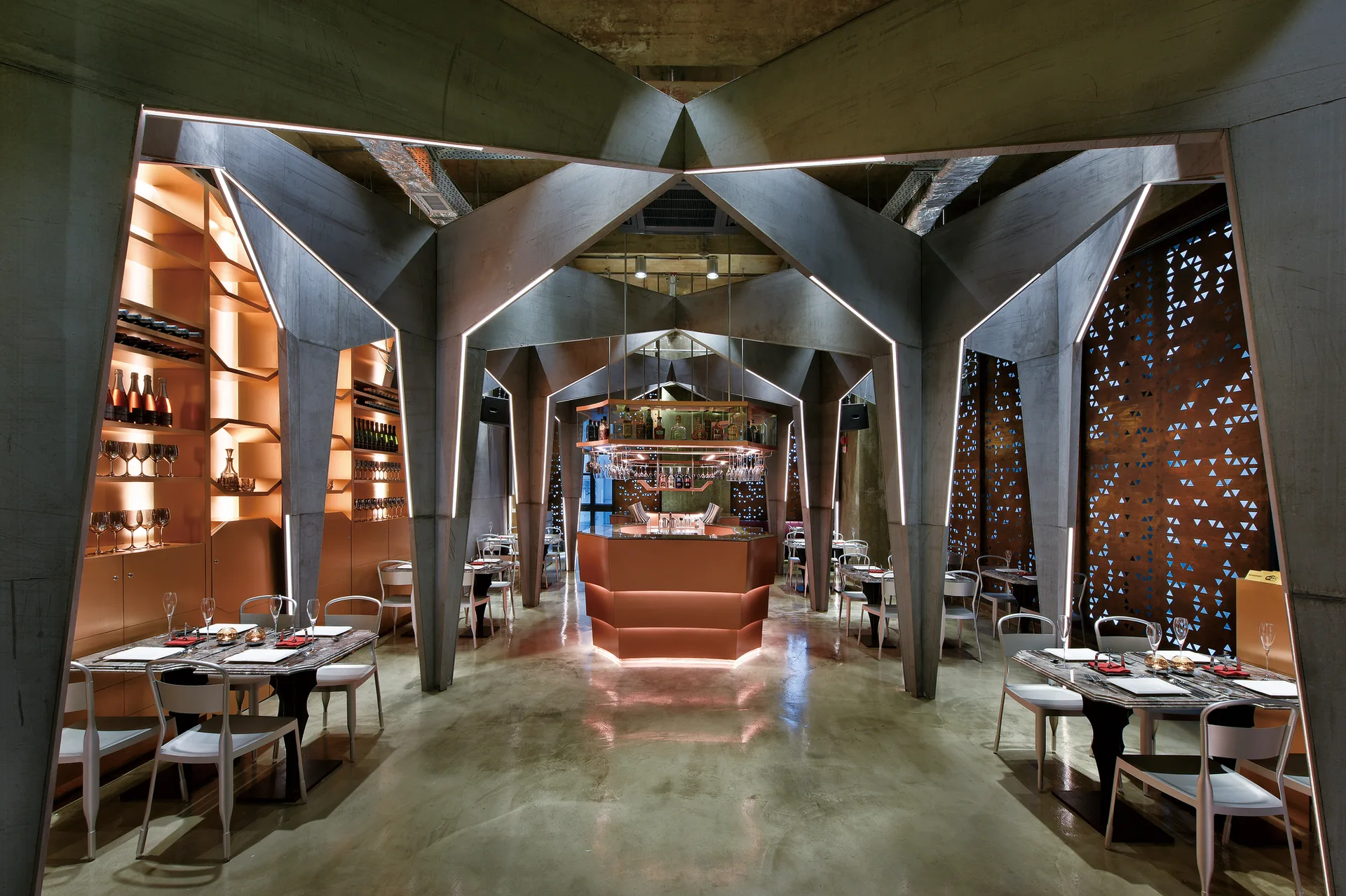 A modern bar features sculptural concrete ceiling beams, a central copper bar counter, and perforated metal privacy screens.