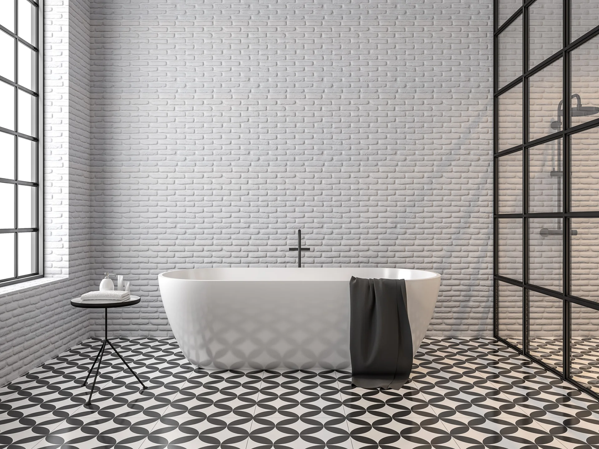 A modern industrial bathroom features a white freestanding bathtub against a painted white brick wall, paired with black and white patterned floor tiles.