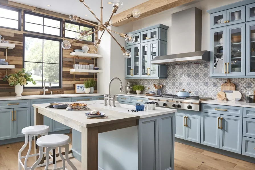 A modern kitchen features light blue cabinetry, a patterned tile backsplash, a central island with stools, and a horizontal wood plank accent wall.