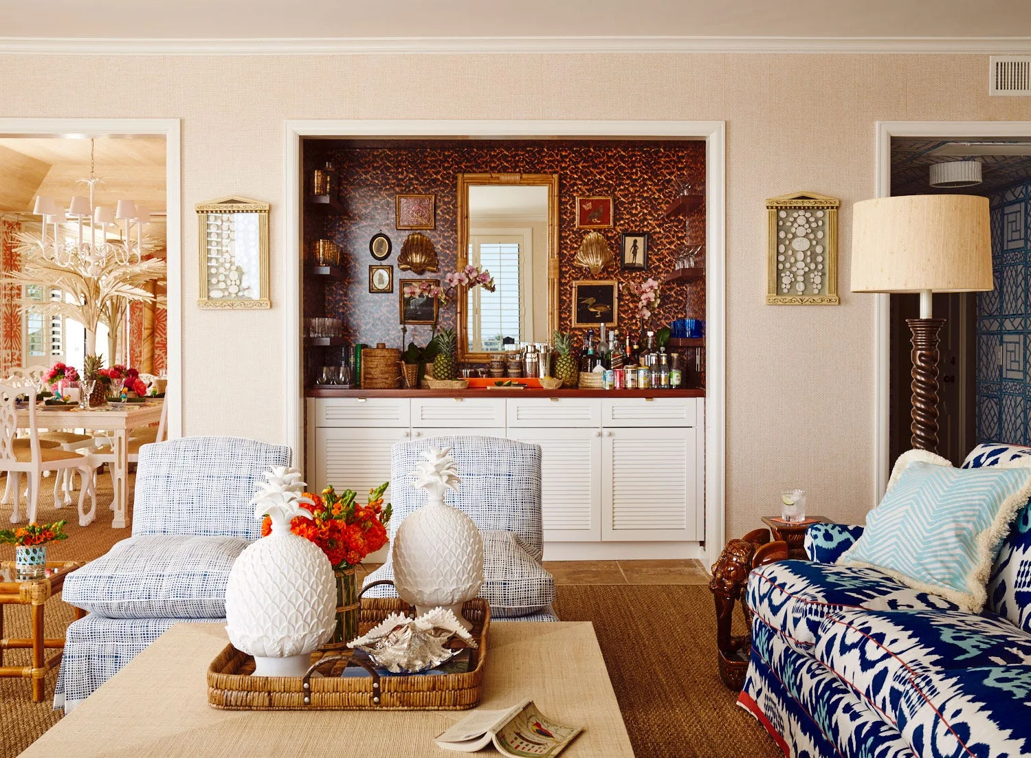 An eclectic living room features blue-patterned seating, a jute rug, and a recessed built-in home bar with a patterned wall covering.