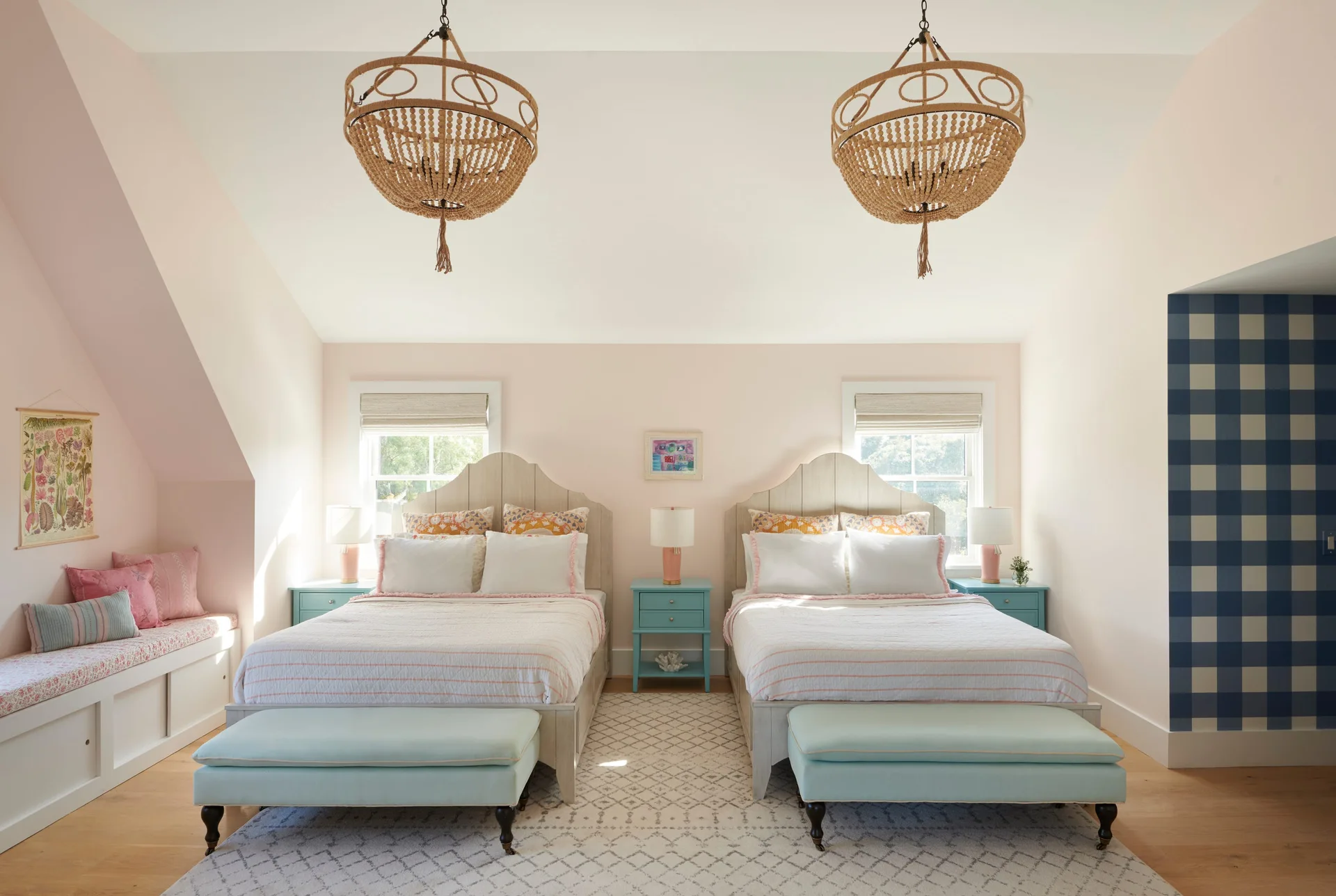 Symmetrically arranged bedroom featuring two beds with light wood headboards, turquoise nightstands, beaded chandeliers, and pale pink walls.