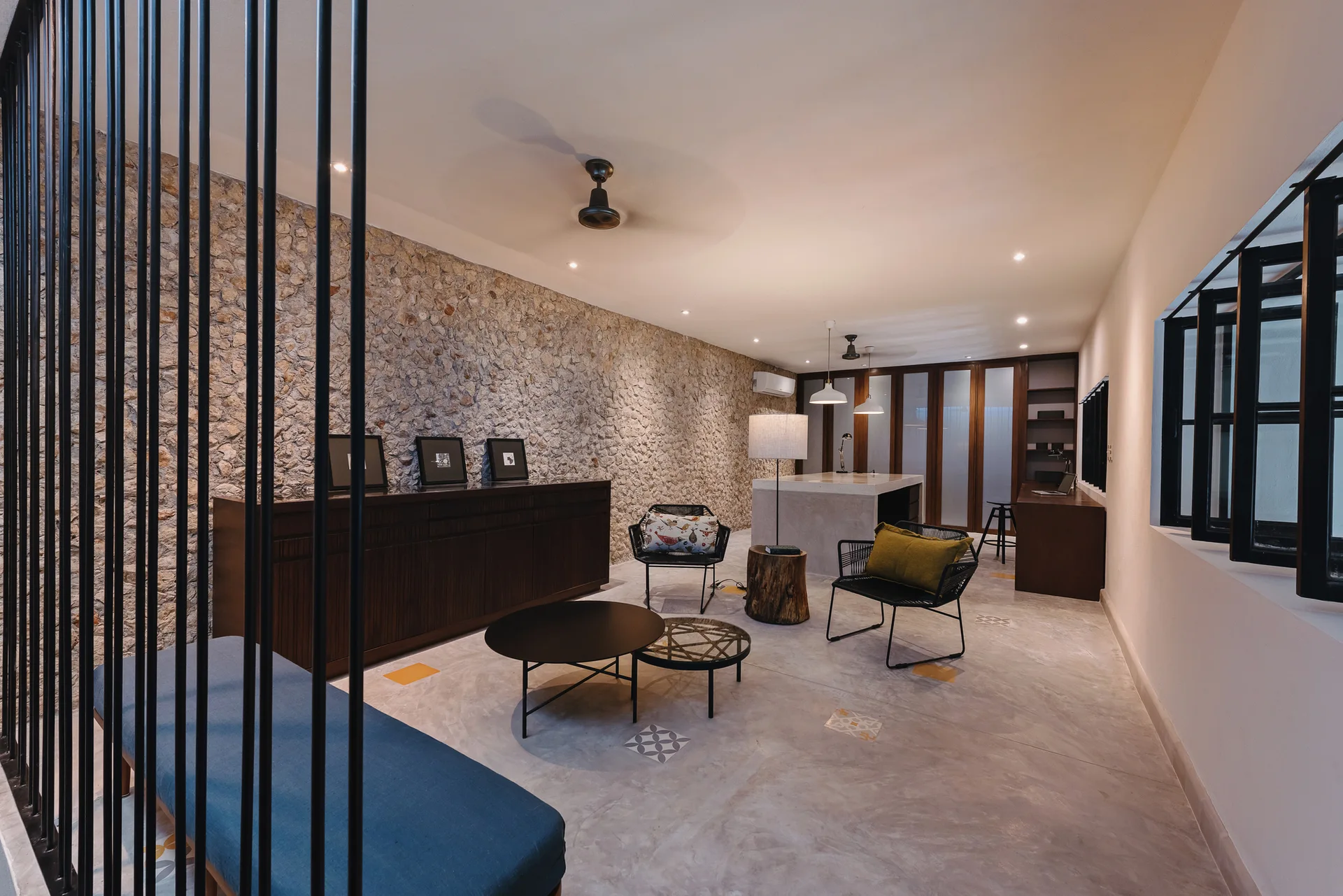 An open-concept living area features a textured stone accent wall, a dark wood sideboard, and black metal screen dividers.