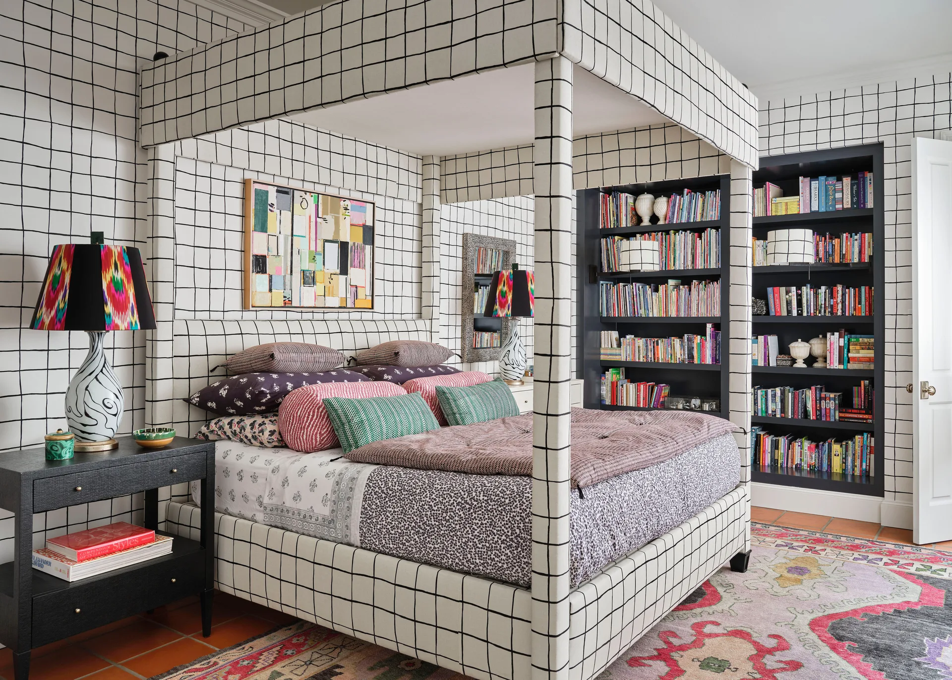 A bedroom features a canopy bed and walls covered in matching black and white grid pattern wallpaper, flanked by built-in bookshelves.