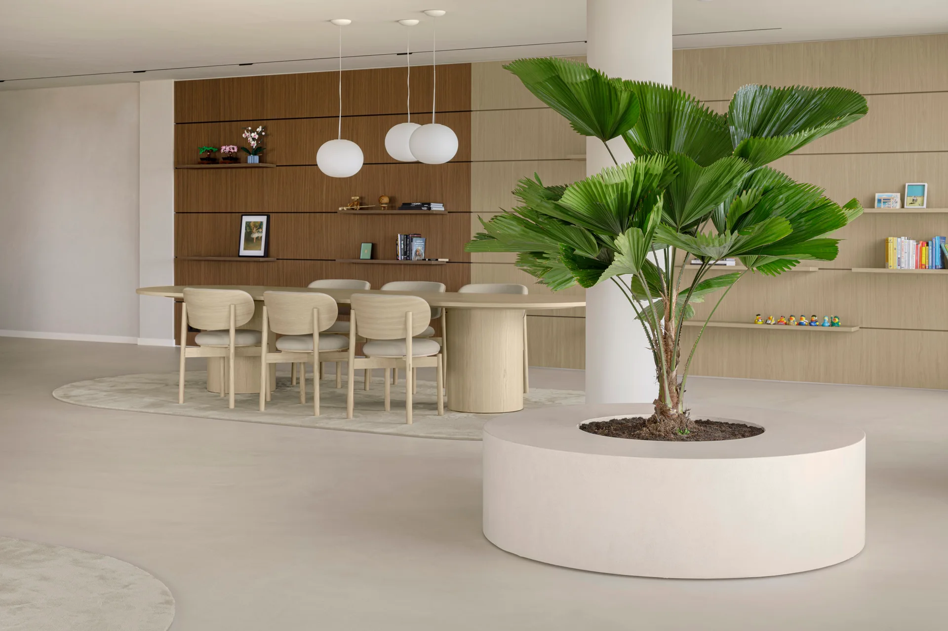 A minimalist dining room features an oval wood table and chairs beneath globe pendant lights, flanked by a slatted wood wall and a large circular planter.