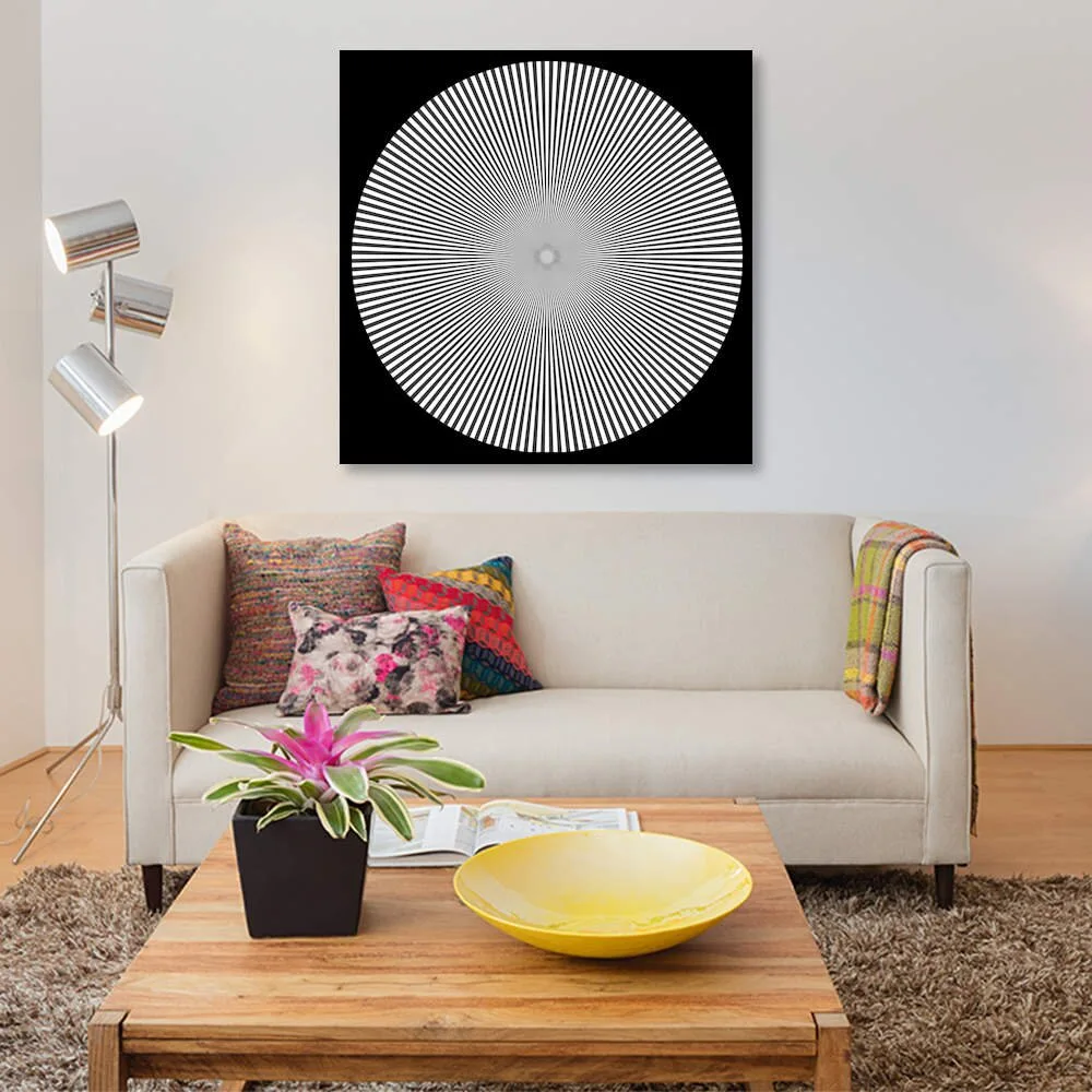 A cream sofa with colorful pillows sits beneath a large black and white geometric art piece in a living room with a wooden coffee table.