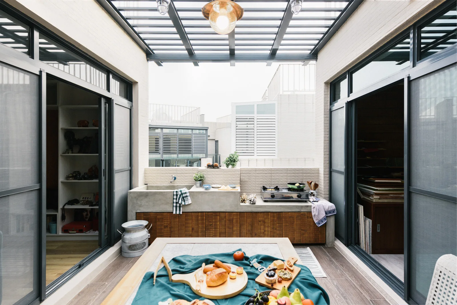 An outdoor kitchen on a covered terrace features a concrete countertop with an integrated sink basin and stove.