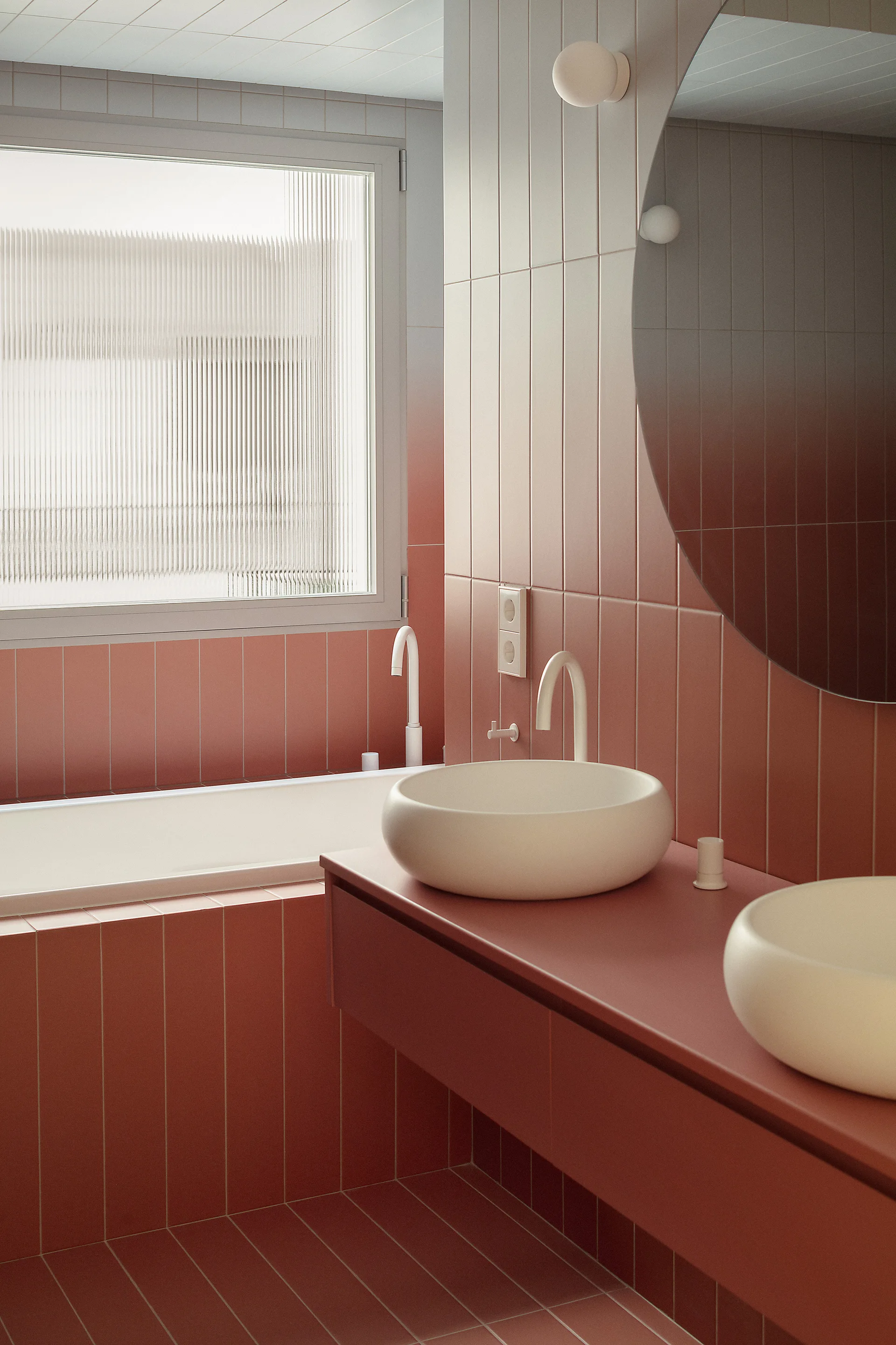 A modern bathroom covered in vertical terracotta tiles with two white rounded vessel sinks, curved faucets, and a built-in tub near a window.