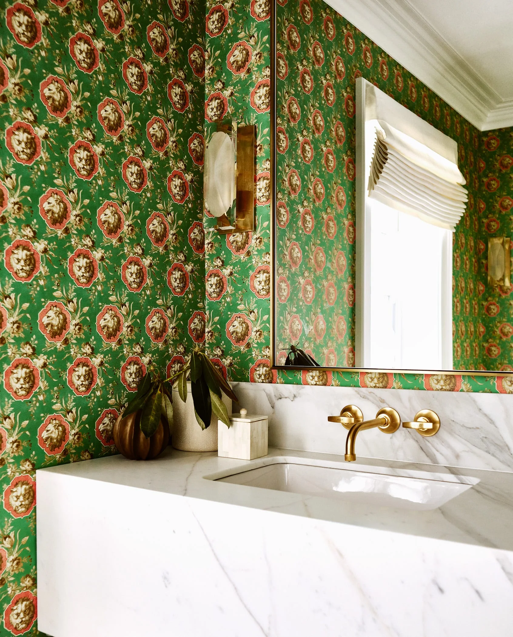 A powder room features green lion-patterned wallpaper, a white marble vanity with a brass wall-mounted faucet, and a large mirror.