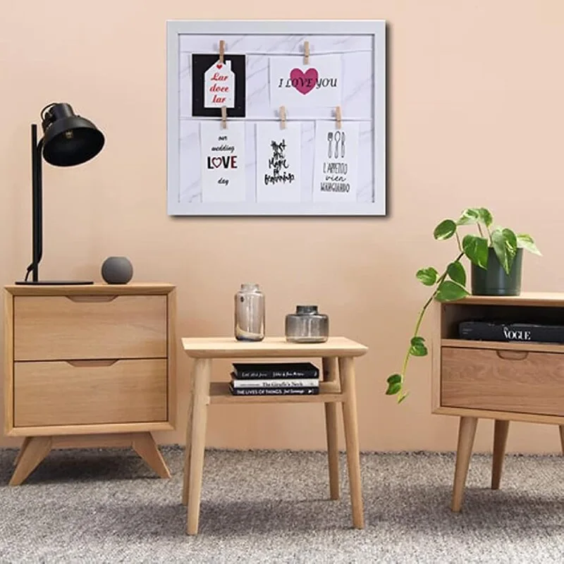 Three light wood tables of varying designs stand against a beige wall on a textured grey carpet.