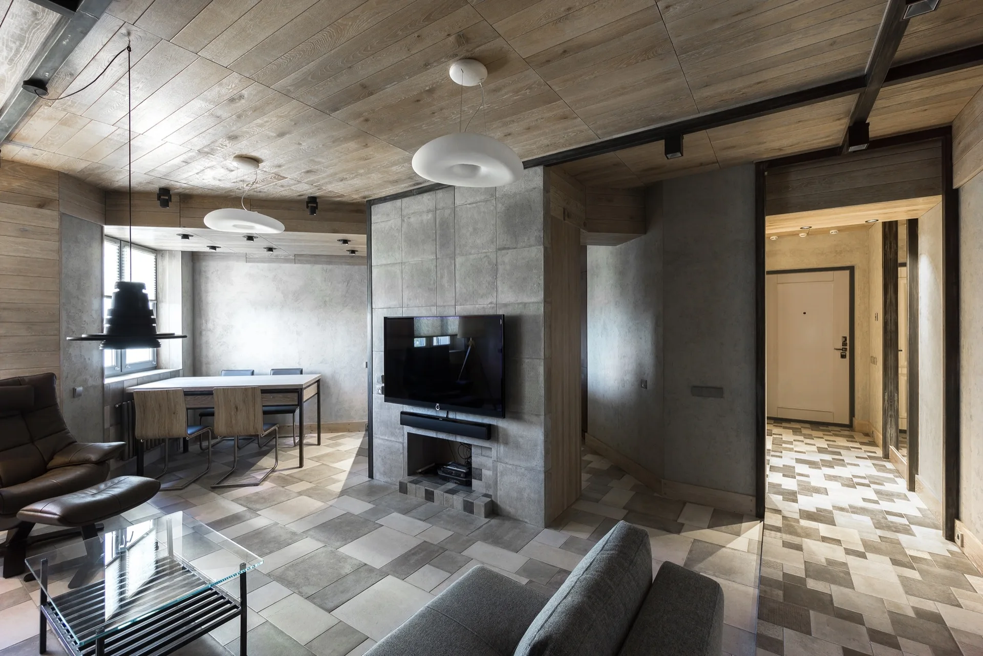 An industrial living room featuring a textured concrete fireplace partition, a wood-plank ceiling, and checkerboard floor tiles.