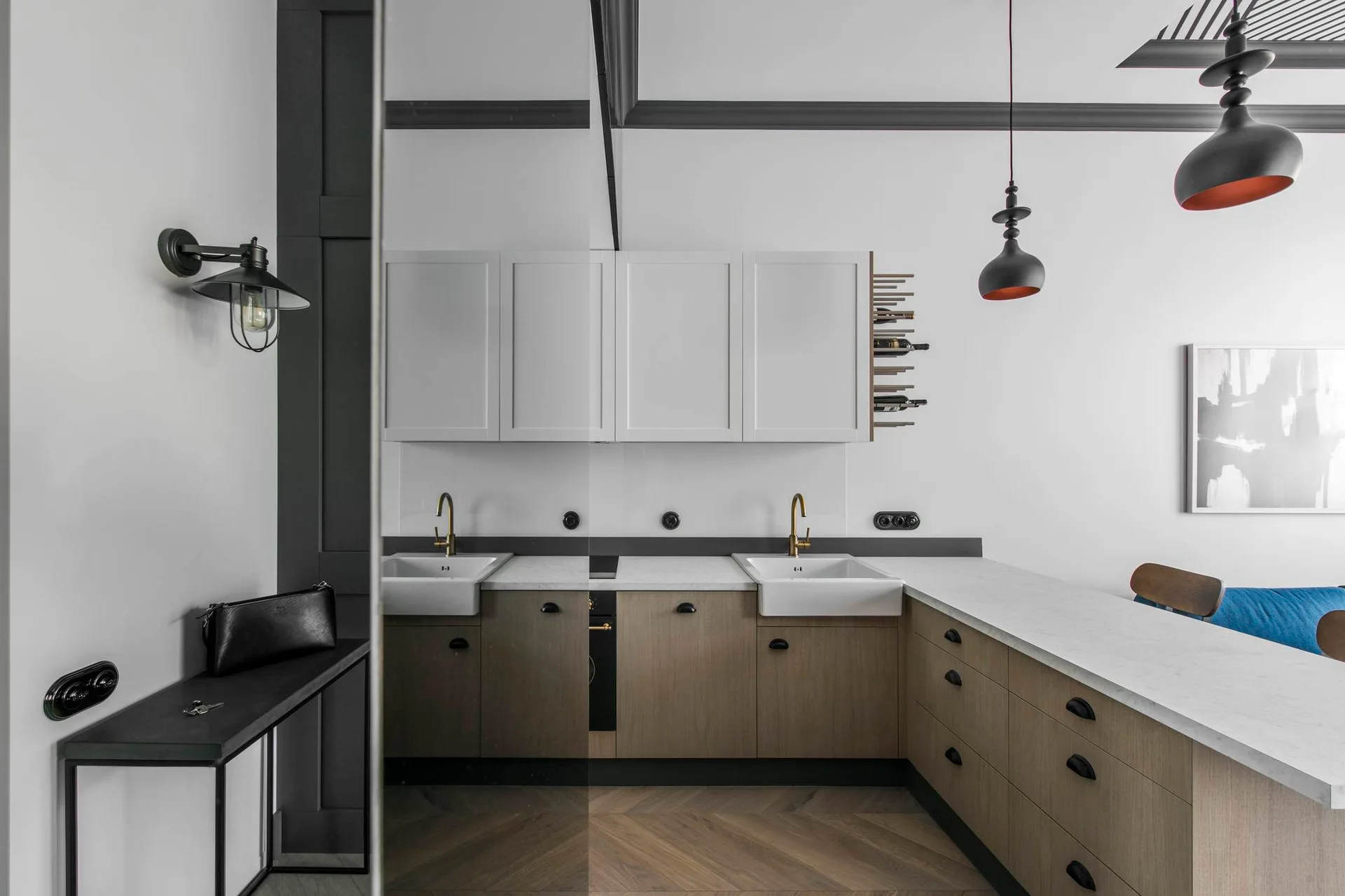 A modern kitchen featuring two-tone cabinetry with wood lower units and white upper units, double farmhouse sinks, and herringbone wood floors.