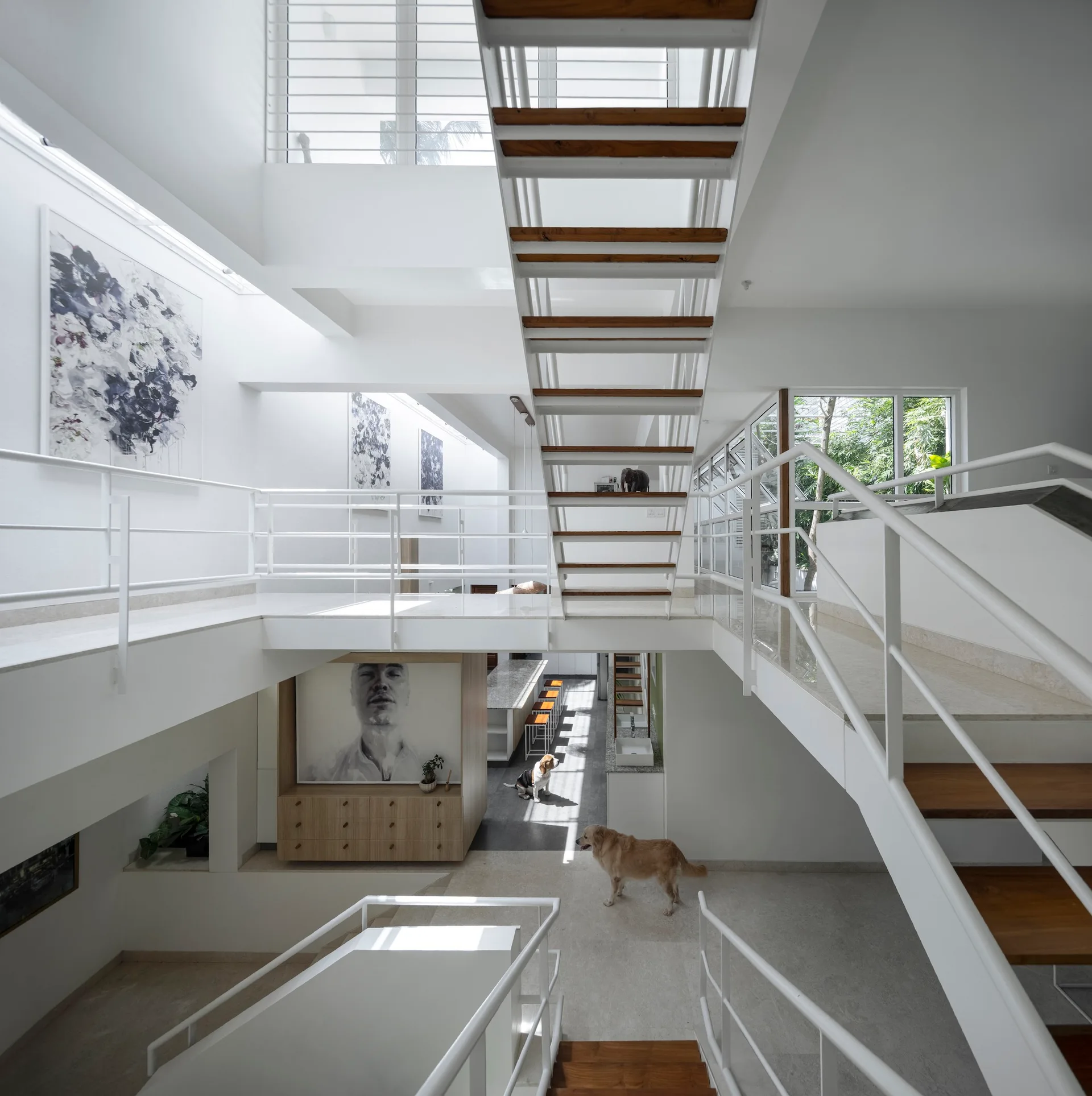 A bright multi-level home interior featuring a central white floating staircase with wood treads, metal railings, and polished stone flooring.