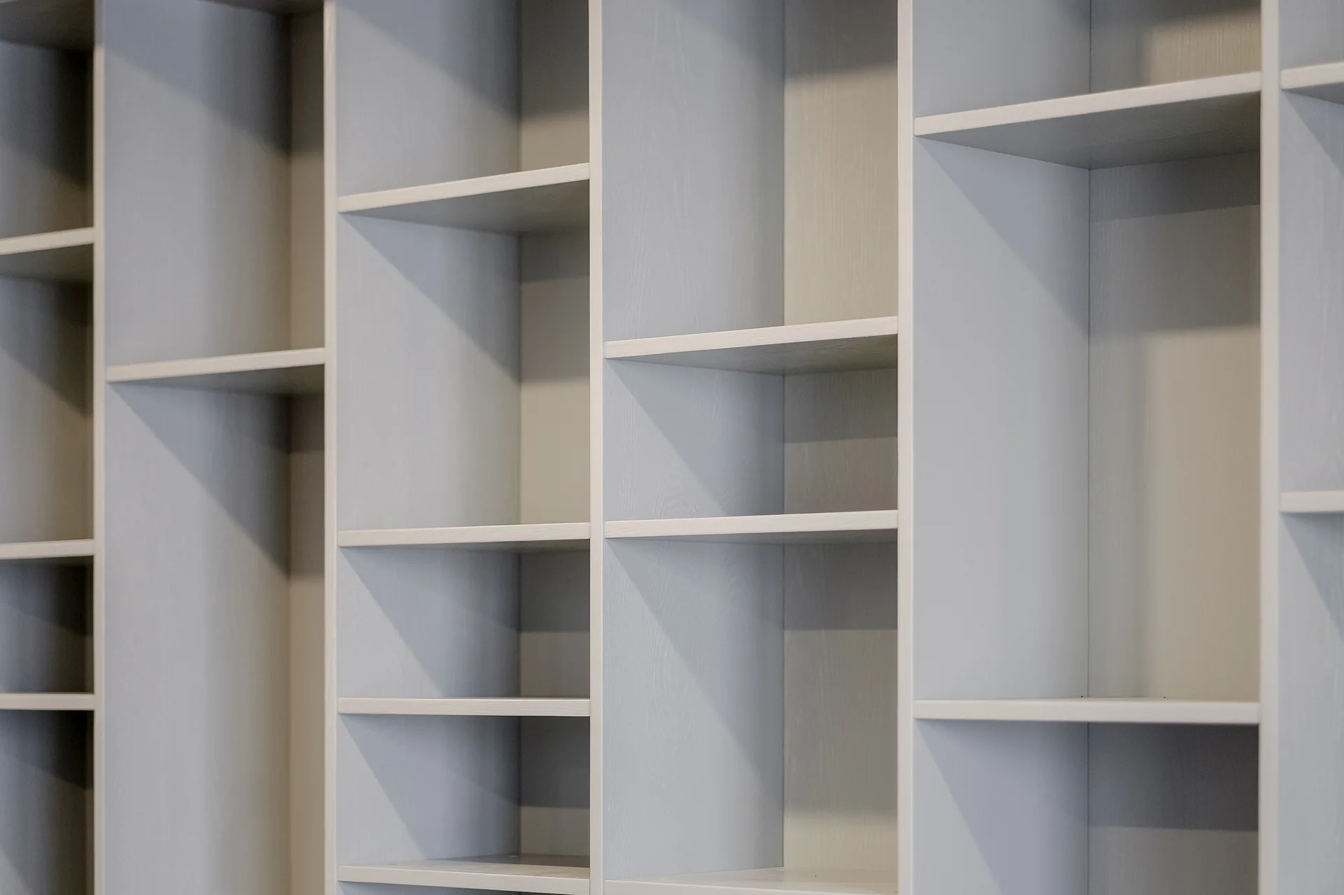 A close-up view of an empty built-in wooden shelving unit with modular compartments and a matte gray stained finish.