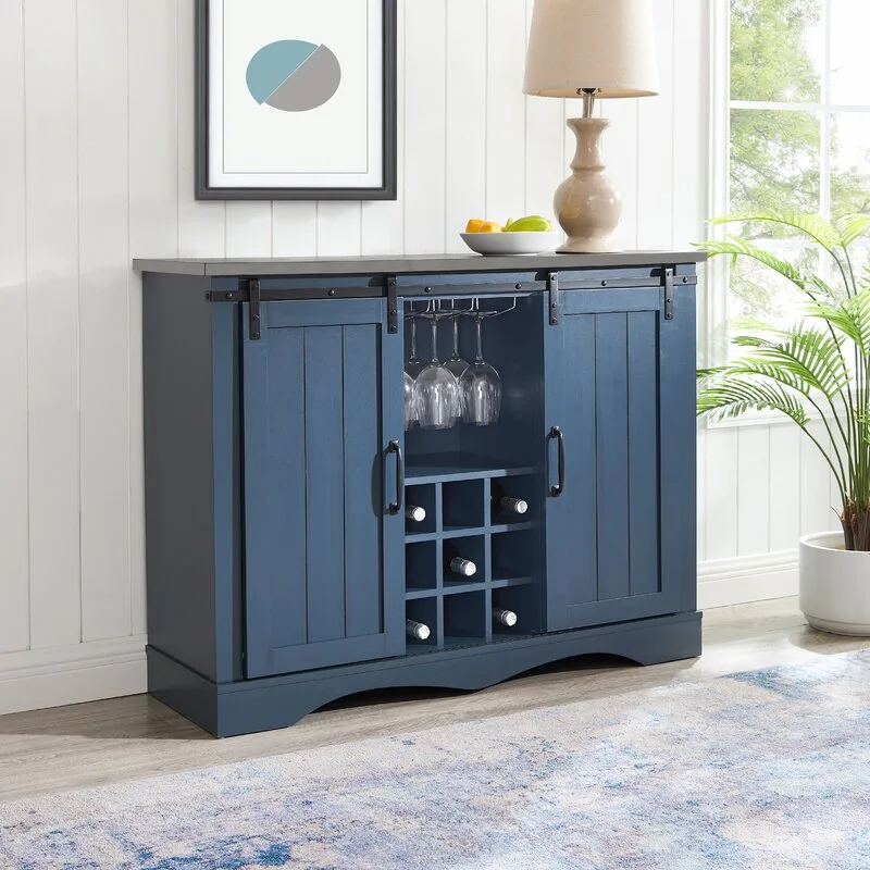 A dark blue wood sideboard with sliding barn doors, a built-in wine rack, and a grey top stands against a white paneled wall.