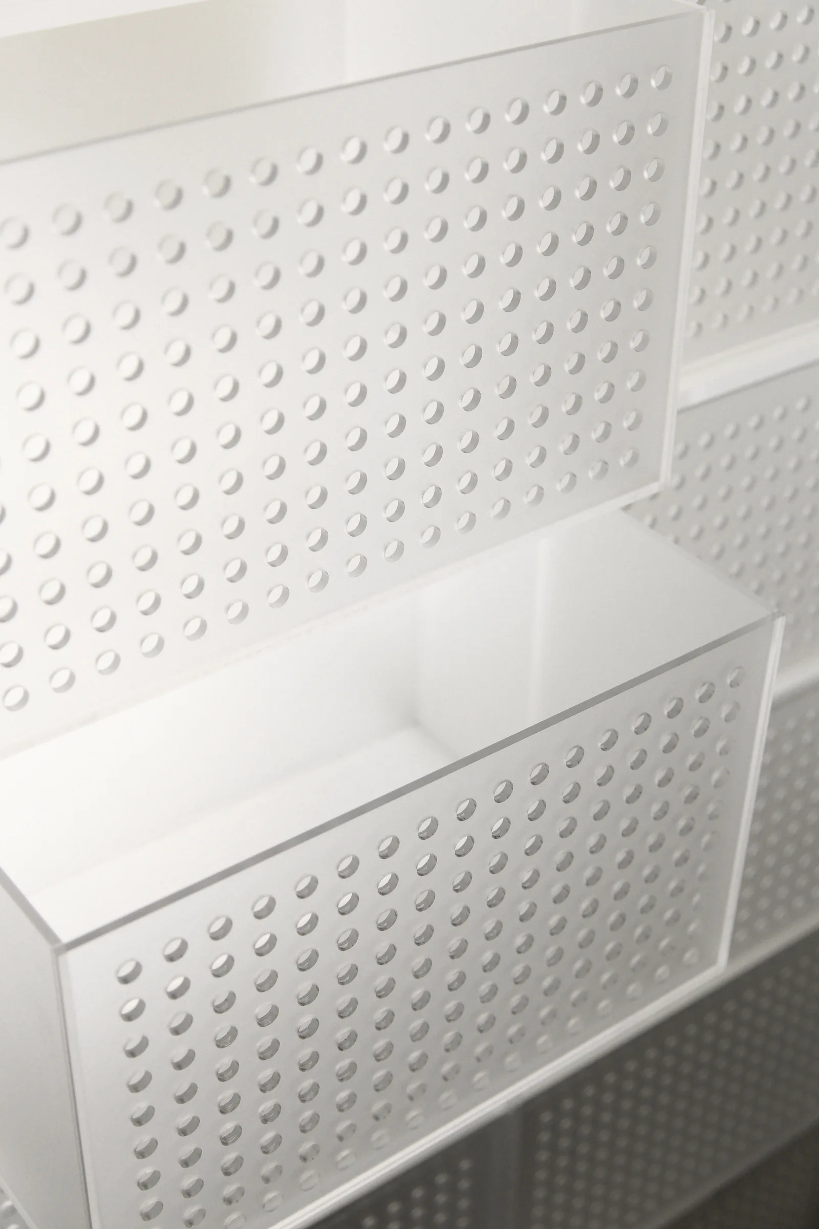 A close-up view of modular white storage bins stacked on top of each other, featuring a repeating pattern of small circular holes.