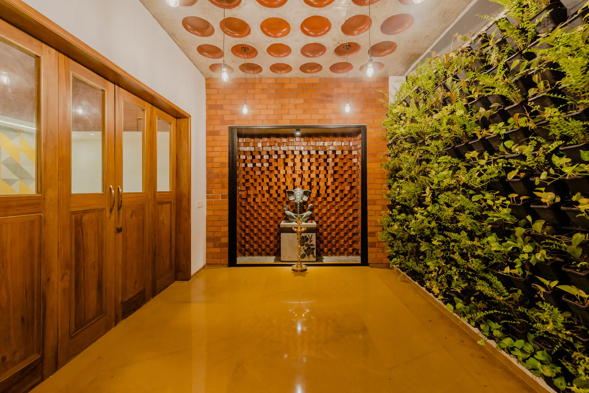 An entryway hallway featuring a polished yellow stone floor, a lush vertical green garden wall, and a recessed brick niche with a stone statue.