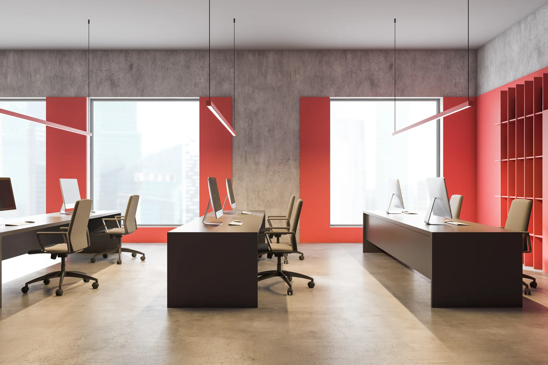 A modern open-plan office features dark minimalist desks, grey swivel chairs, concrete walls, and vibrant red accent panels by large windows.