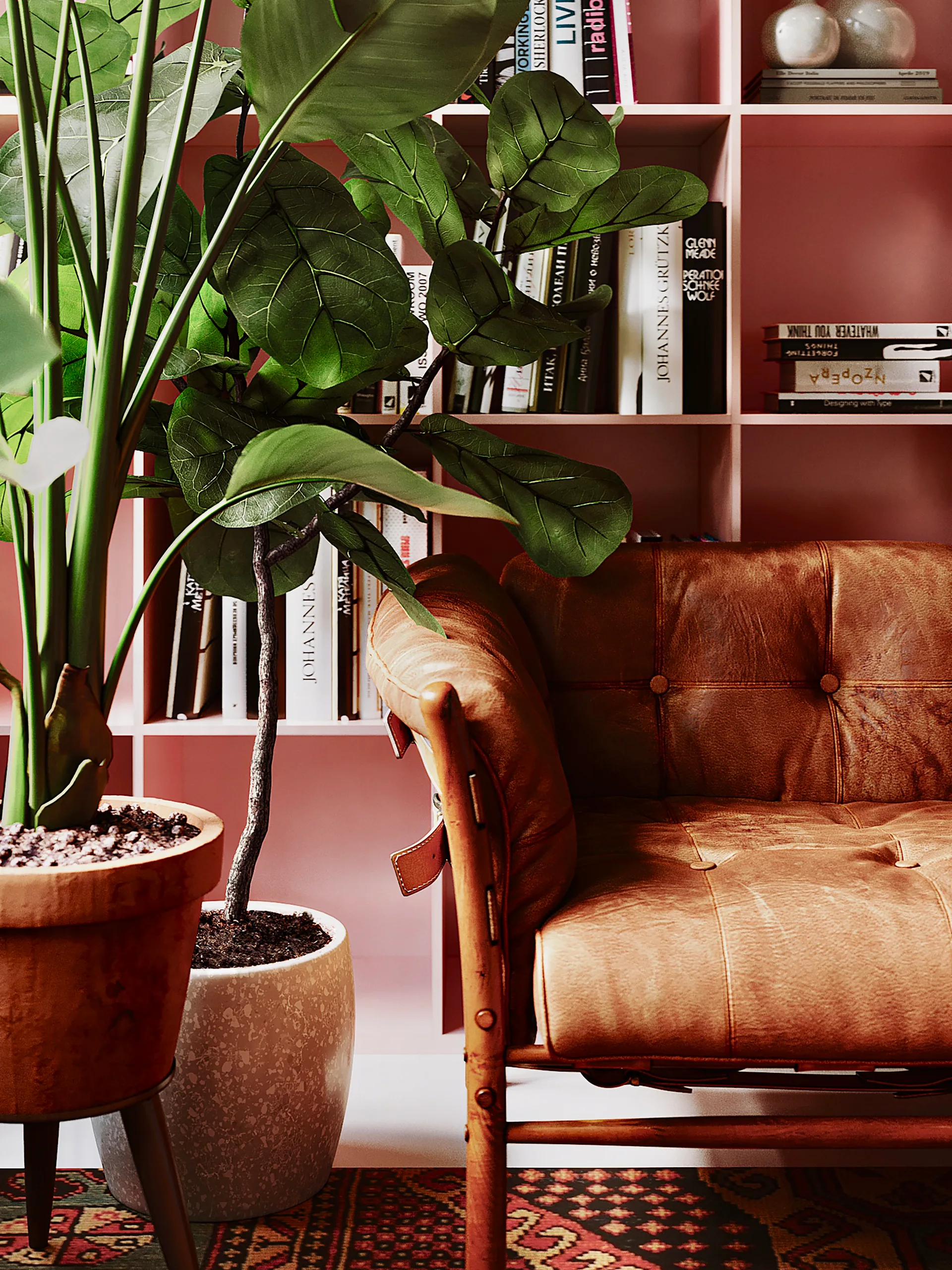A tufted tan leather armchair sits next to large potted plants in front of a painted pink built-in bookshelf filled with books.