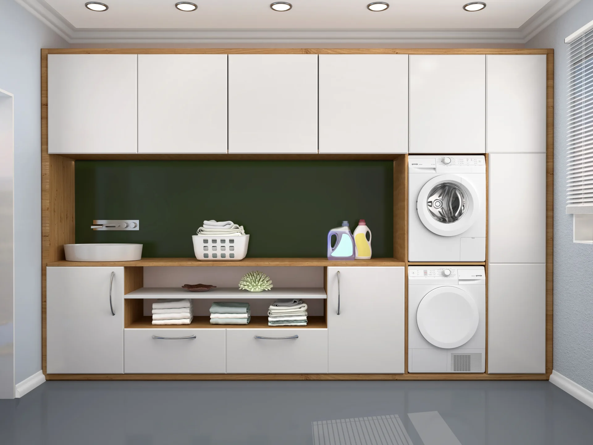 A modern laundry room with built-in white and wood cabinetry, stacked washer and dryer, a vessel sink, and a dark green backsplash.