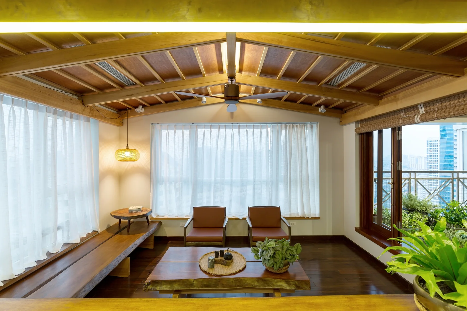 Japandi style living room featuring an exposed timber ceiling, two brown leather armchairs, a live edge coffee table, and sheer curtains.