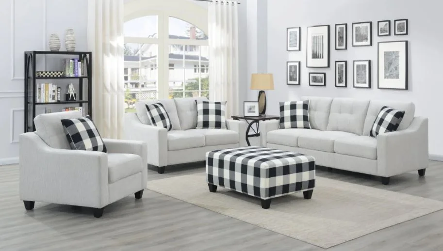 A light gray living room furniture set featuring a sofa, loveseat, and armchair arranged around a black and white buffalo check ottoman.