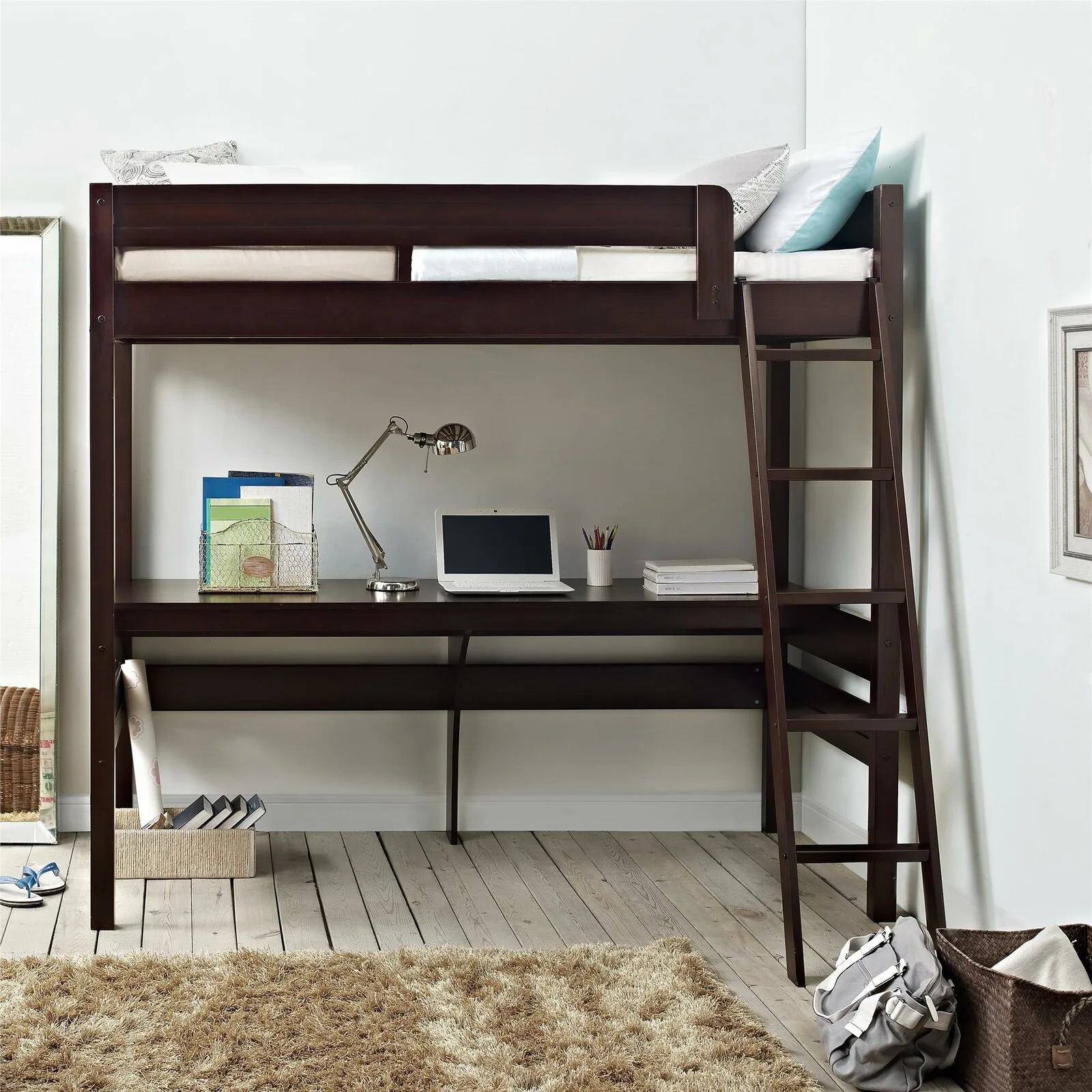 A dark wood loft bed with a built-in desk and ladder stands on light wood floors beside a textured shag rug.